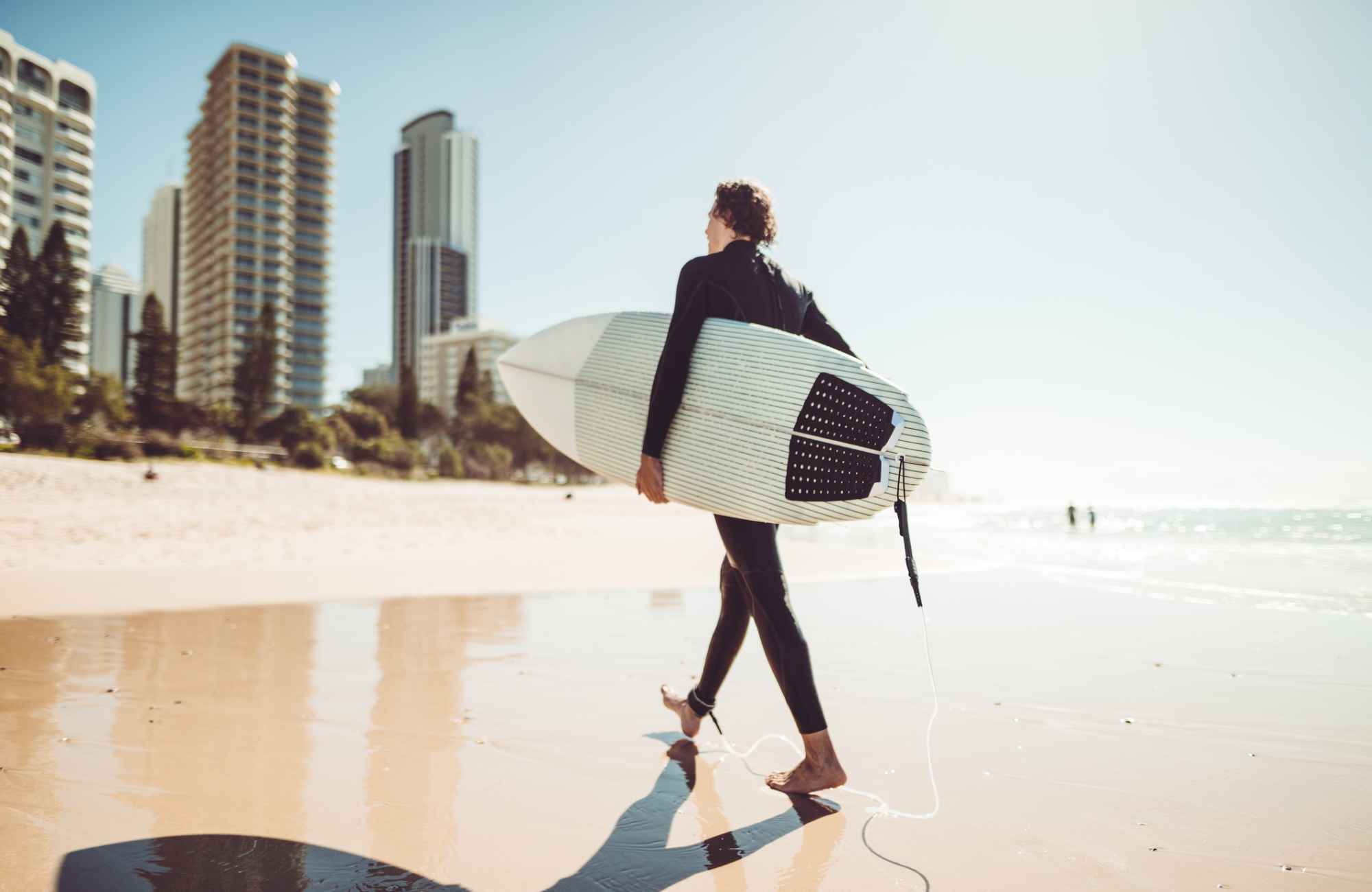 surfer walking in surfers paradise beach in australia surfer walking in surfers paradise beach in australia