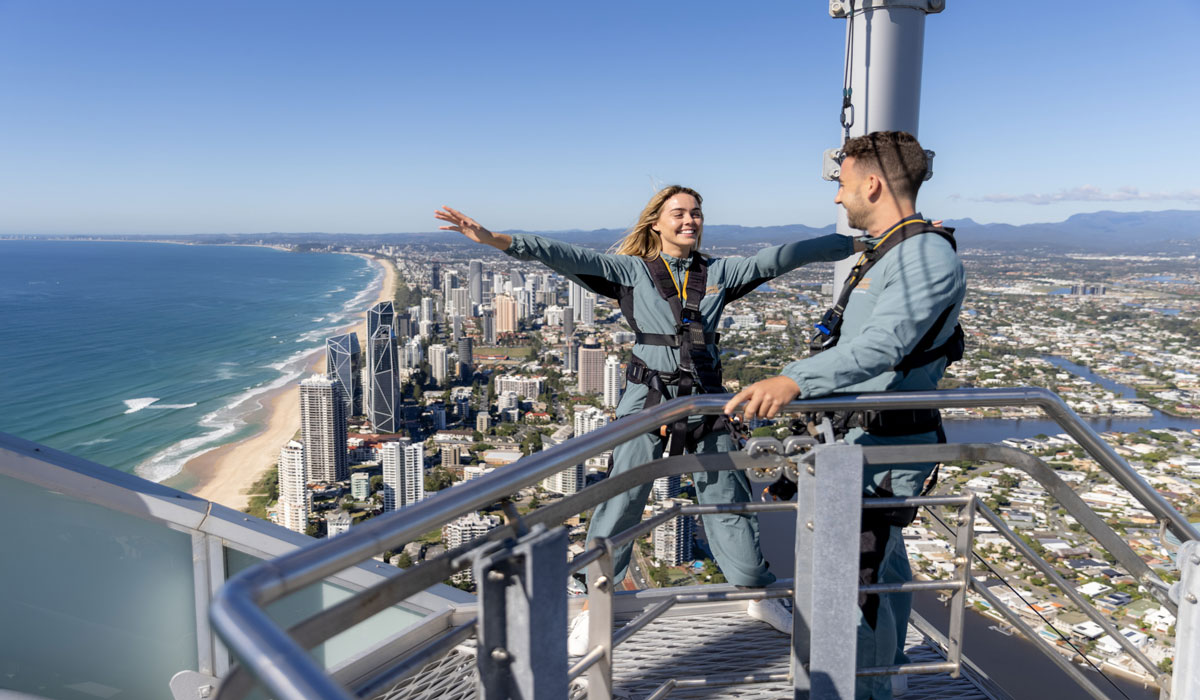 Two climbers at the top a skyscraper building, looking out at a view of the Gold Coast
