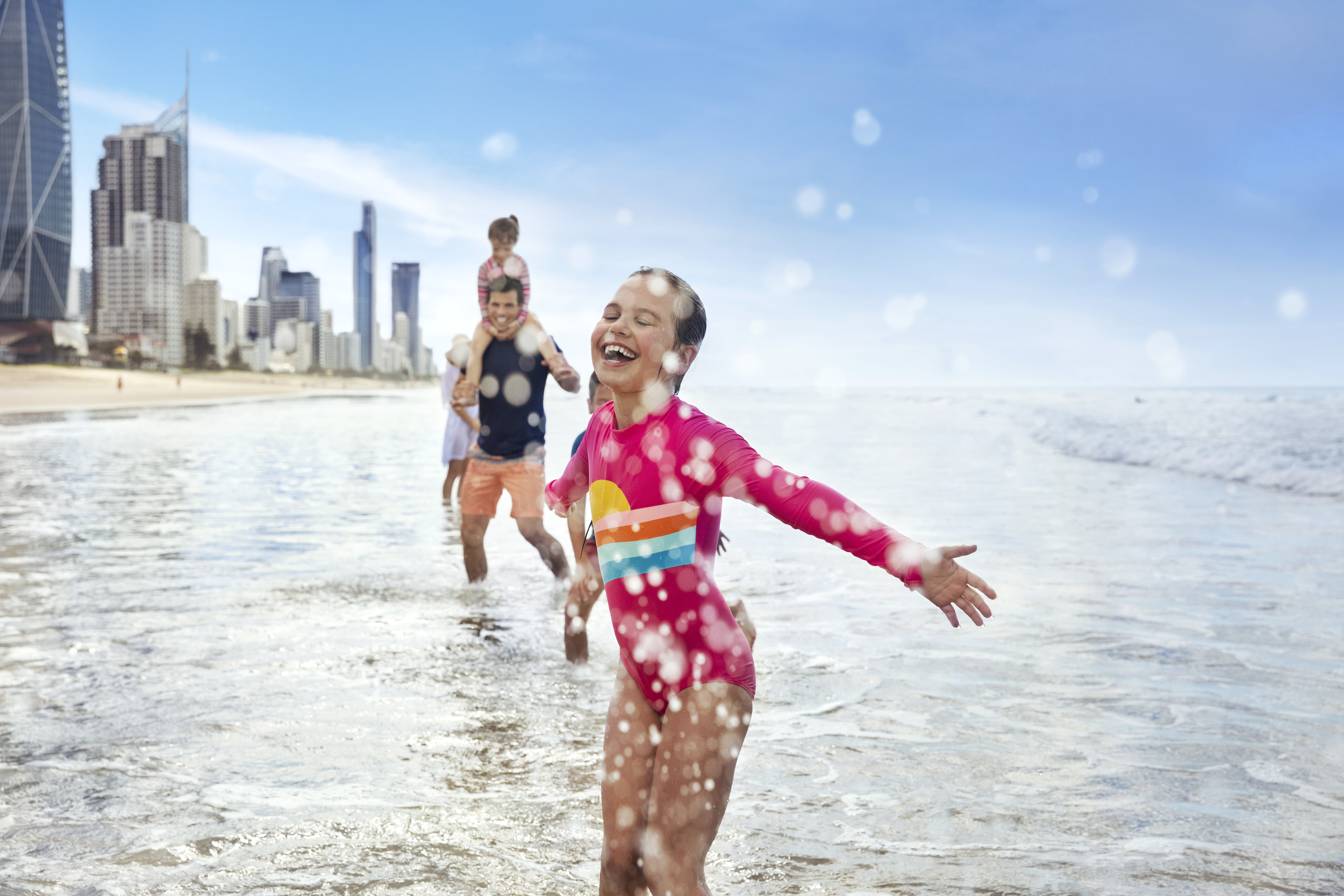 Family running through the water, on the beach