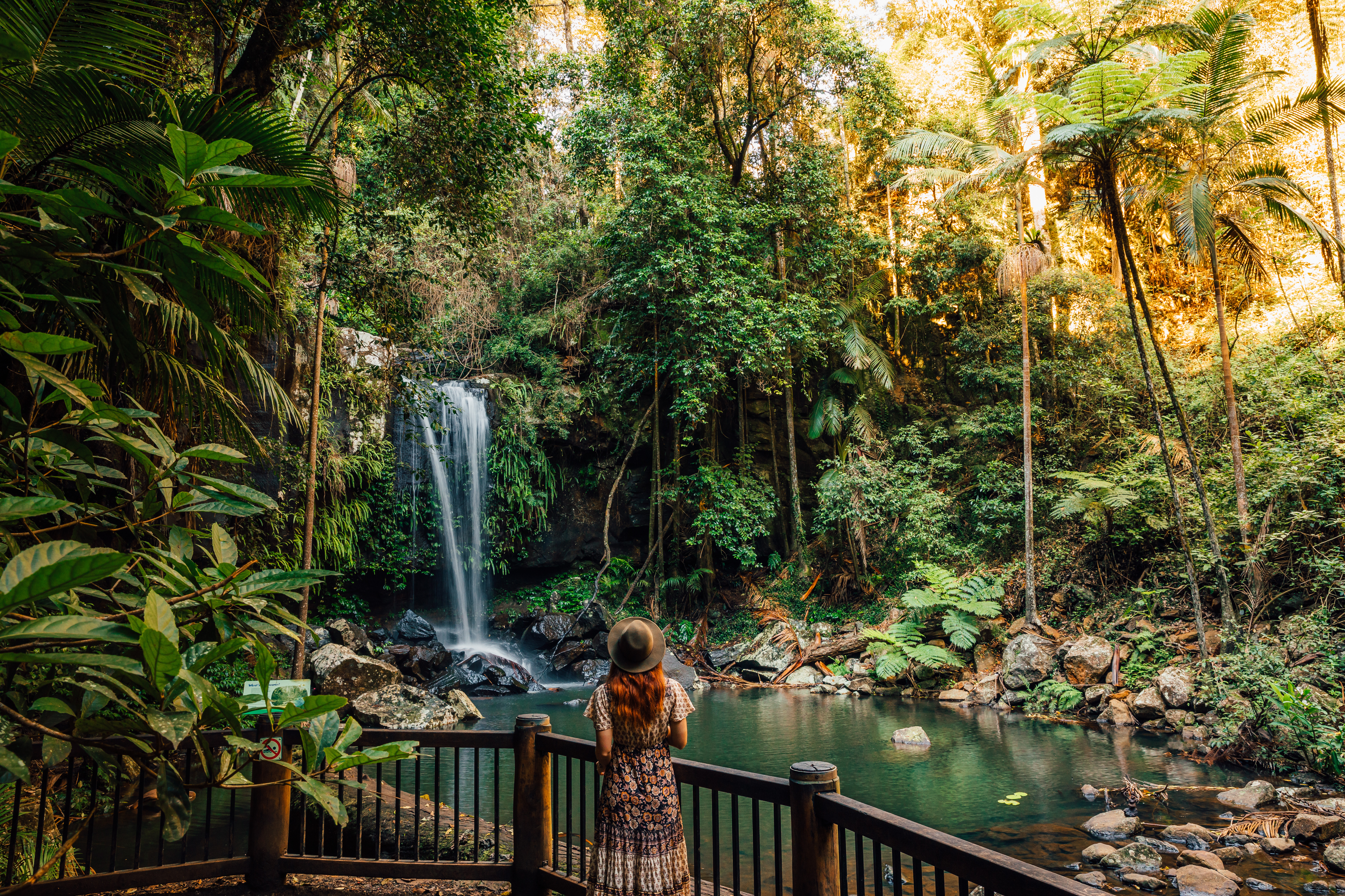 A woman in dress looks out onto a waterfall