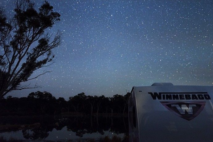 A campervan at night in front of a dark sky full of stars A campervan at night in front of a dark sky full of stars