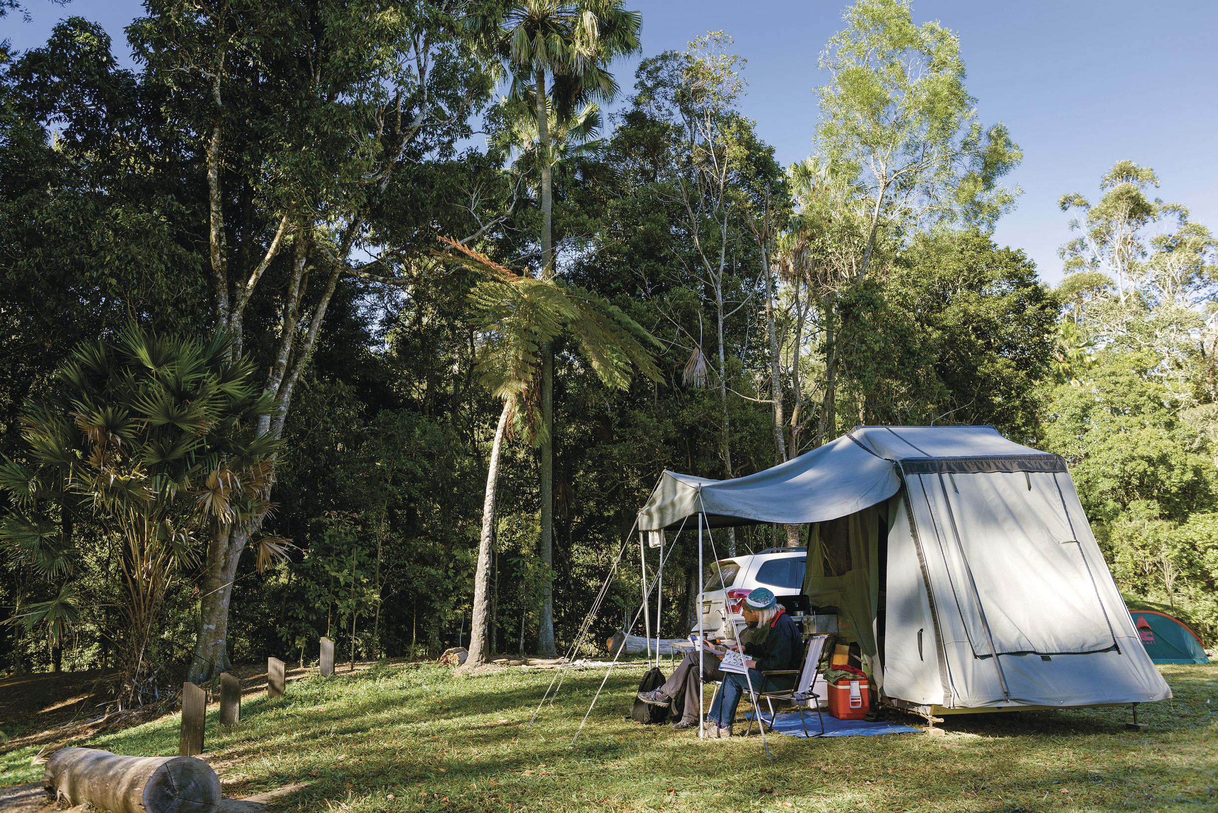 People sitting outside tent in camping ground People sitting outside tent in camping ground