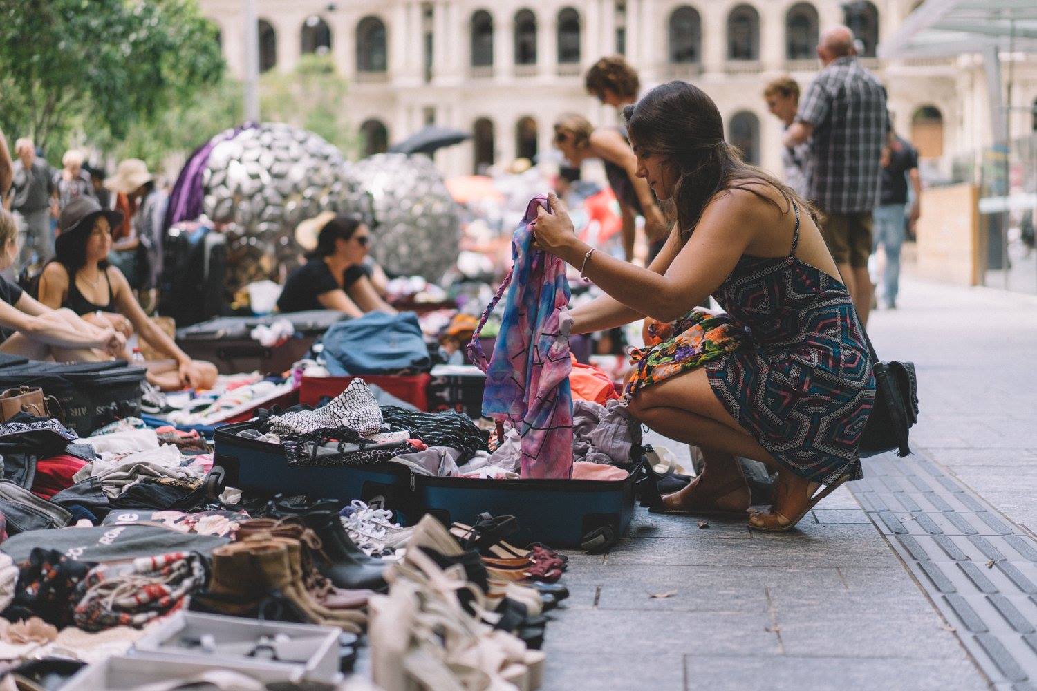 Woman holds dress while looking through suitcases of clothes at the Suitcase Rummage markets in Brisbane Woman holds dress while looking through suitcases of clothes at the Suitcase Rummage markets in Brisbane
