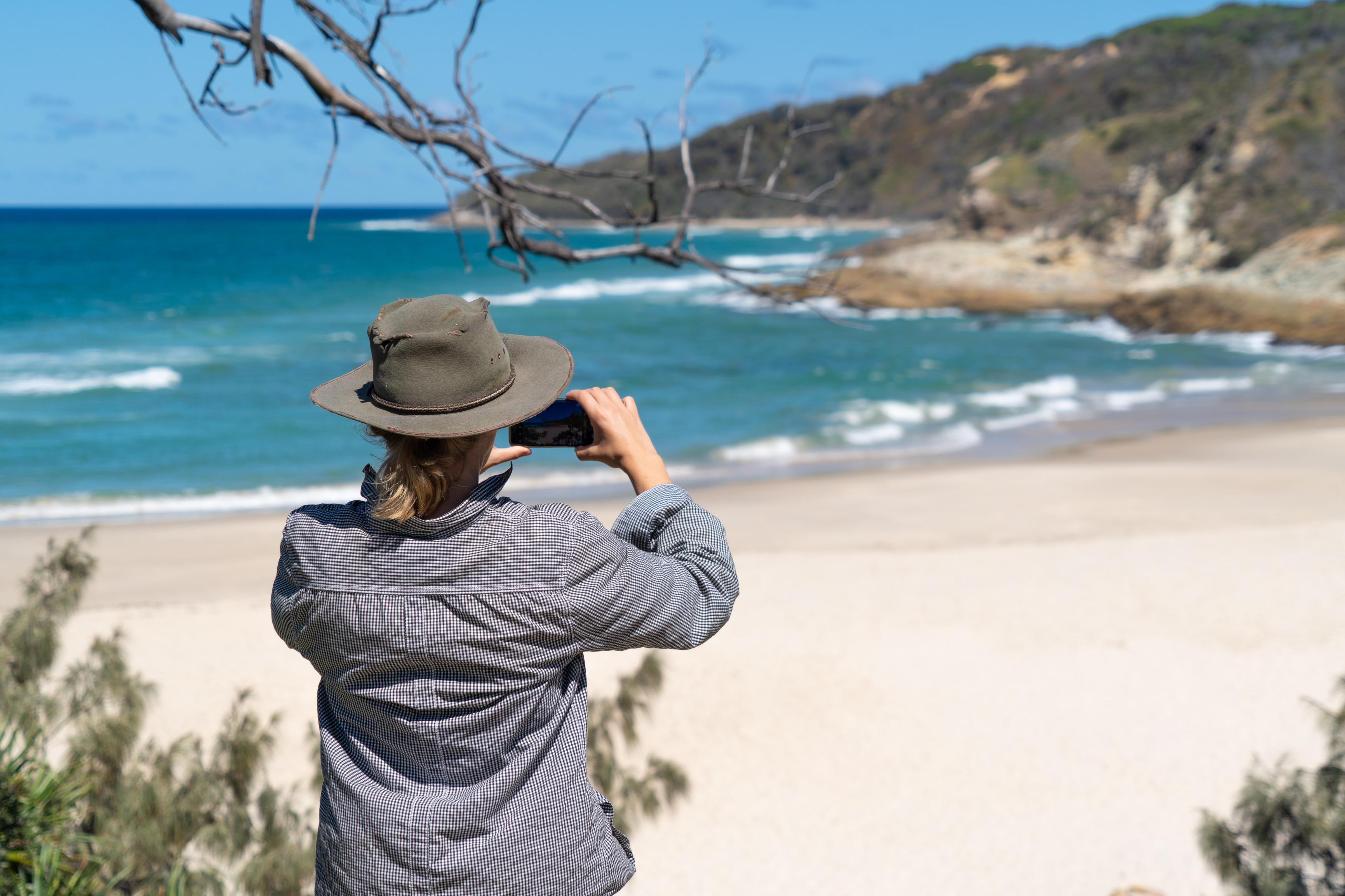 A woman looking out through binoculars at Honeymoon Bay beach