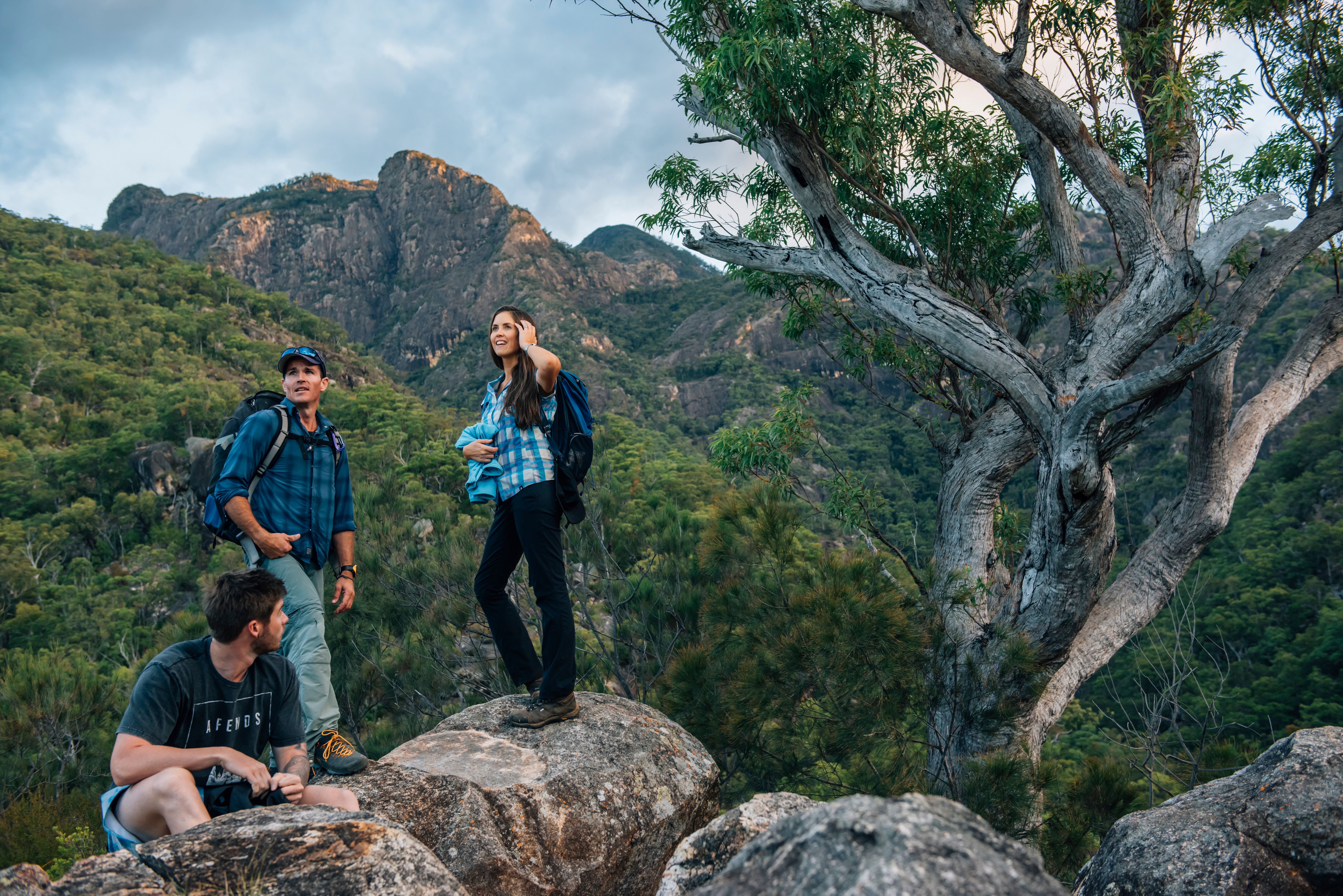 Hikers standing along a rugged walk with large mountain range in the background