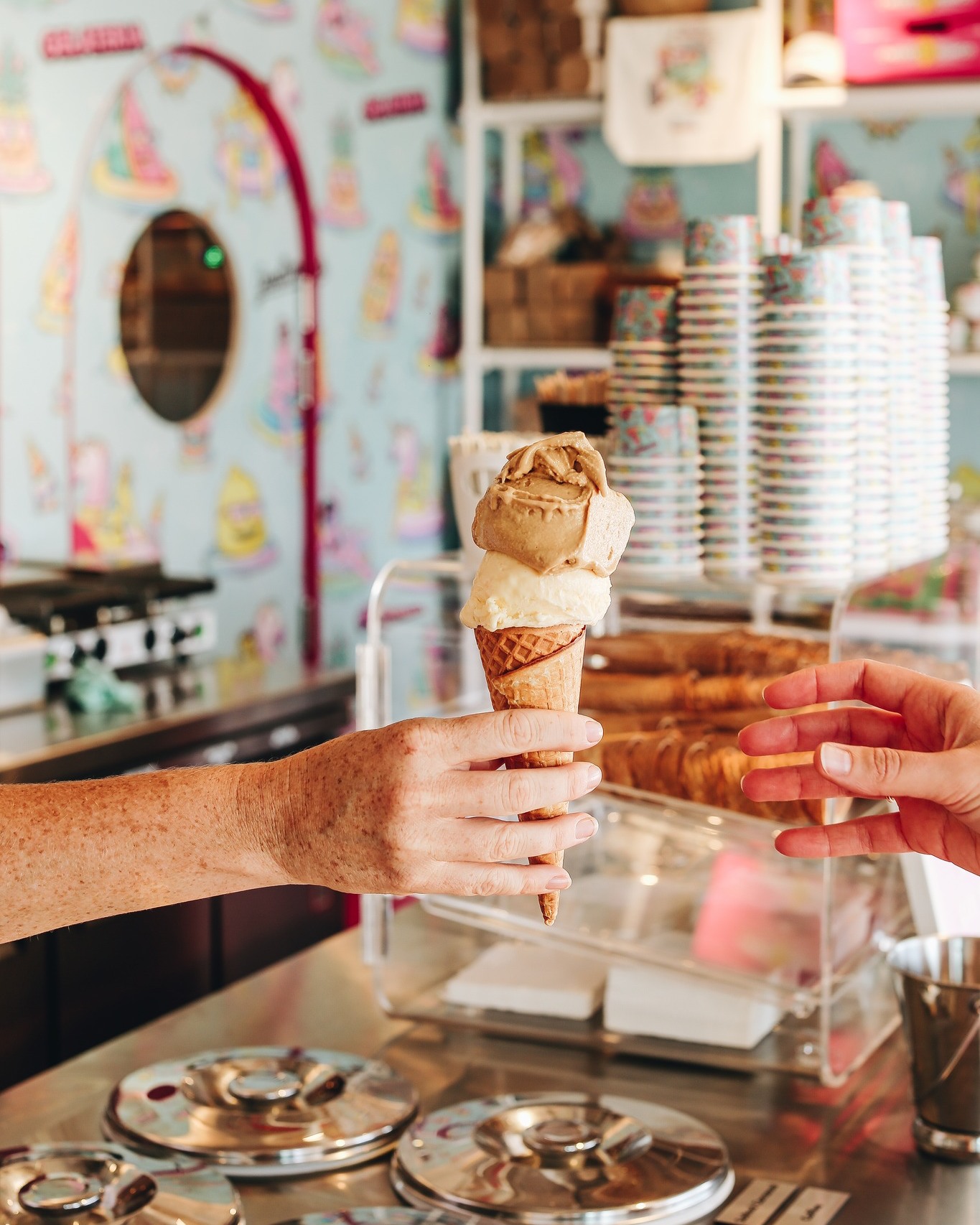 Close up of a server passing a two-scoop gelato cone to a customer at Goodtimes Gelateria, Howard Smith Wharves Close up of a server passing a two-scoop gelato cone to a customer at Goodtimes Gelateria, Howard Smith Wharves