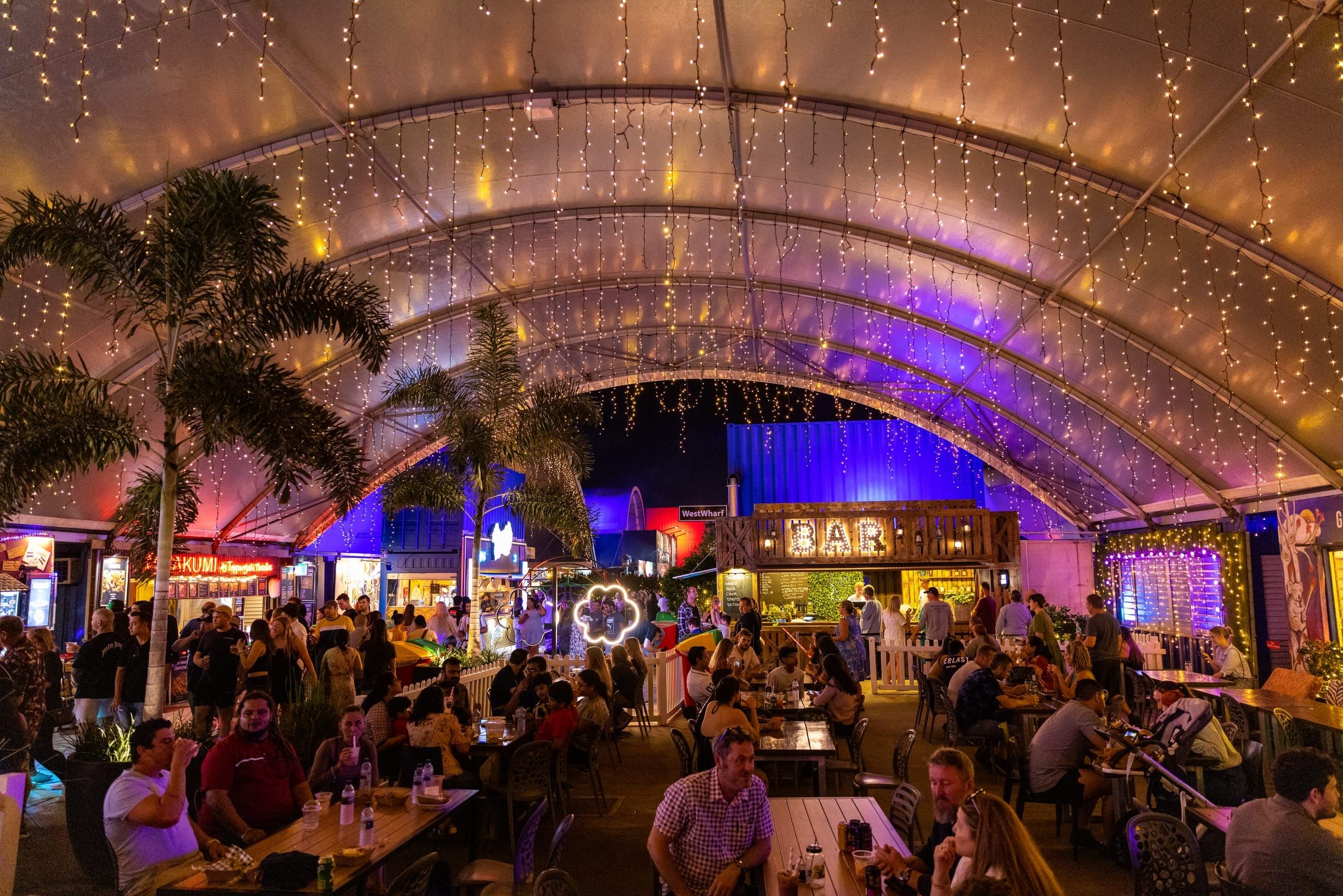 Tables of people fill an open-air bar at Eat Street night market