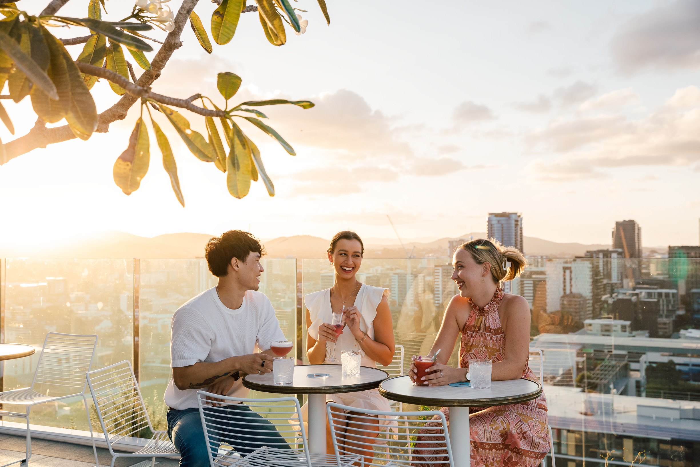 Group of friends enjoying a drink at Lina Rooftop as the sun sets over the city