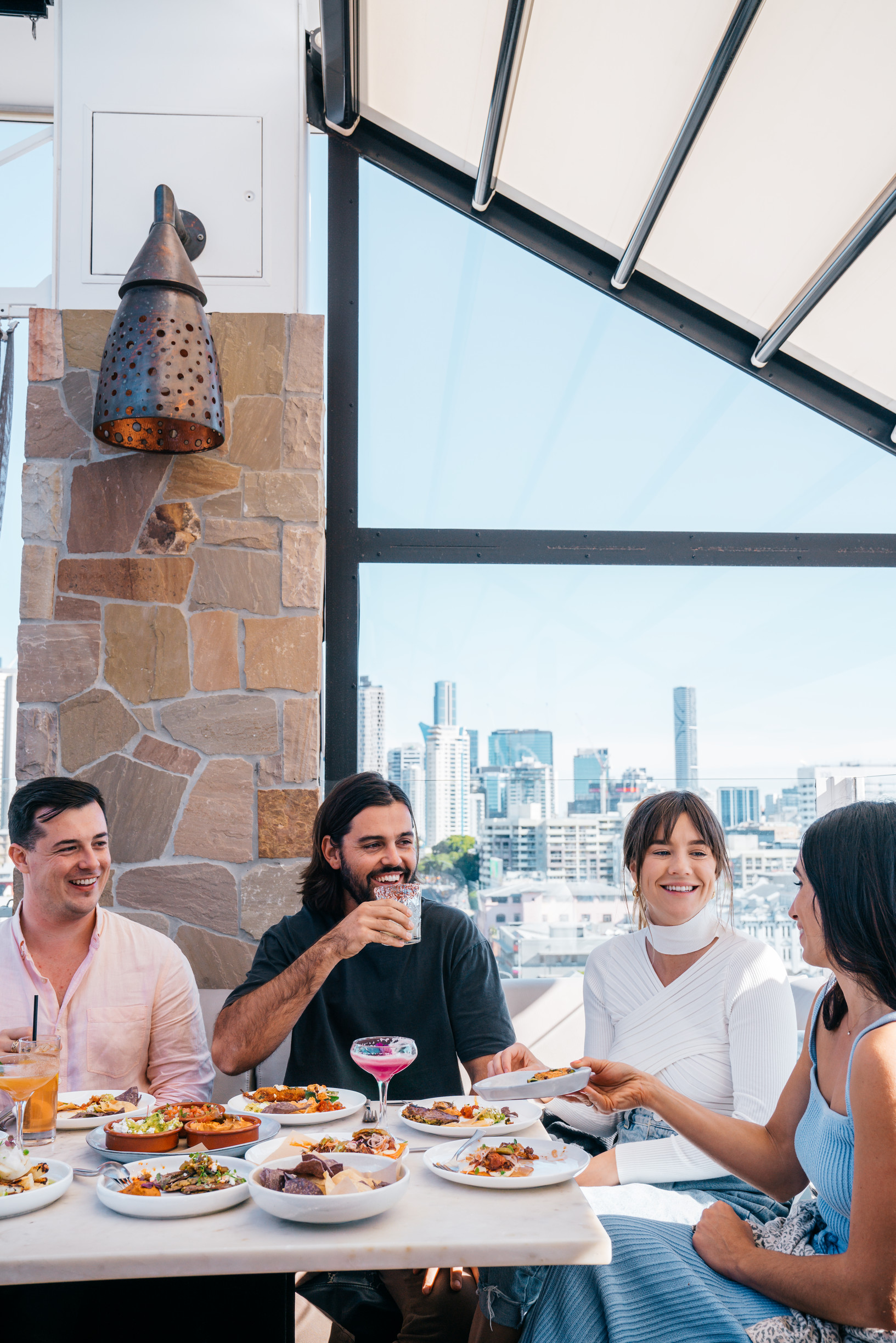 Group dining at Maya Mexican rooftop restaurant and bar, with city skyline in background