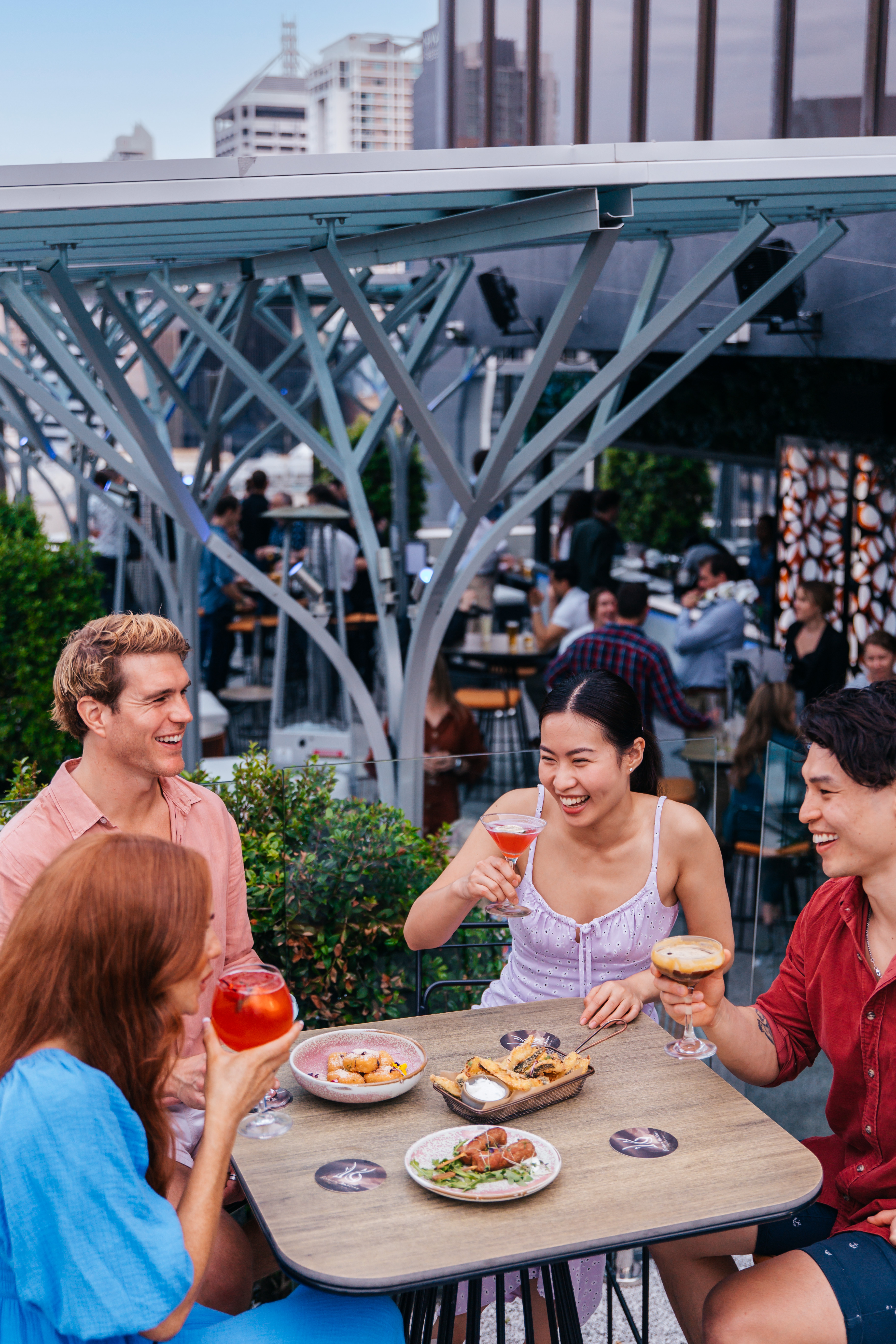 Friends relax and sip drinks at a Brisbane rooftop bar, Sixteen Antlers