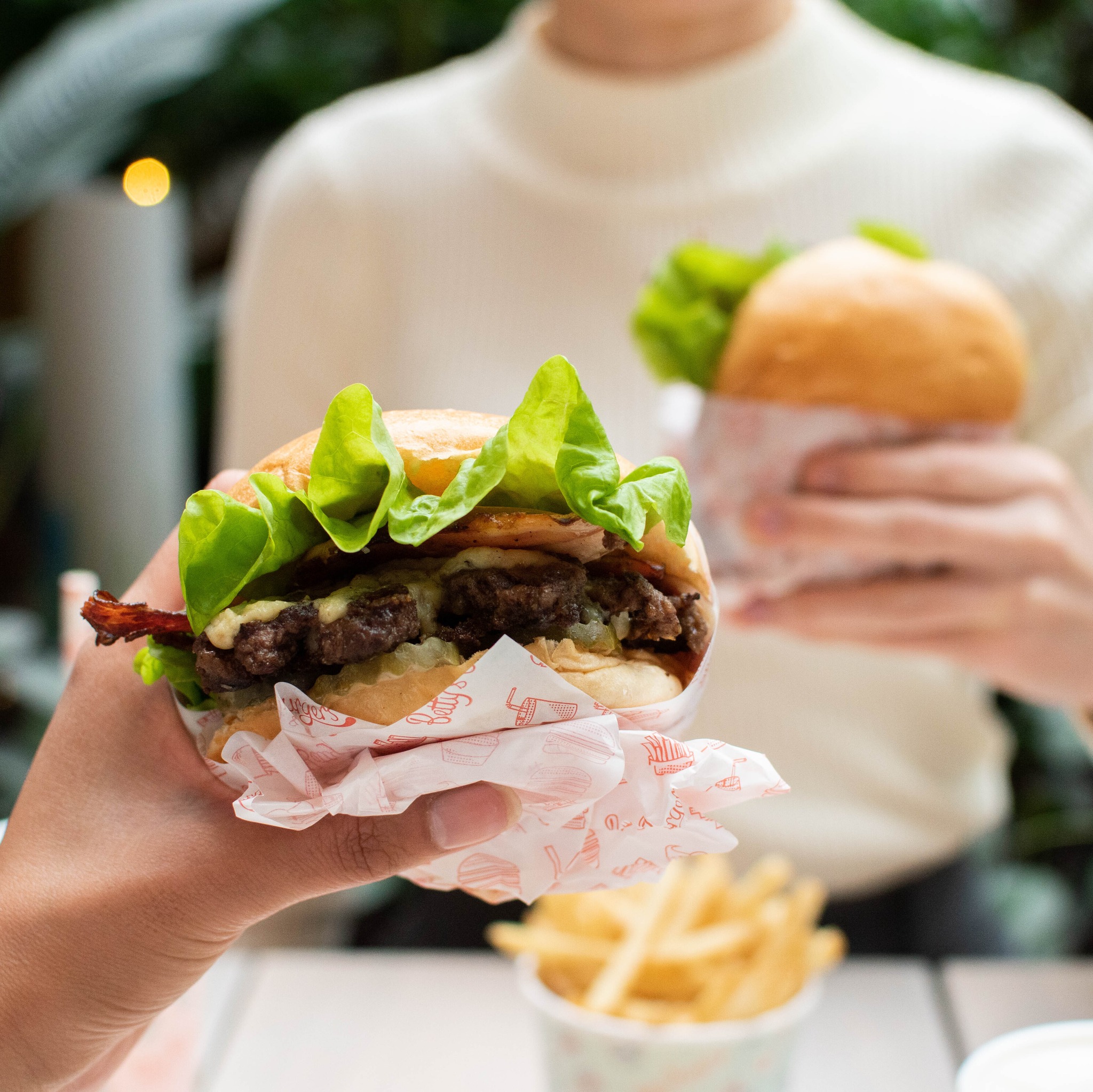 Close up of a hand holding a loaded beef burger from Betty's Burgers Close up of a hand holding a loaded beef burger from Betty's Burgers