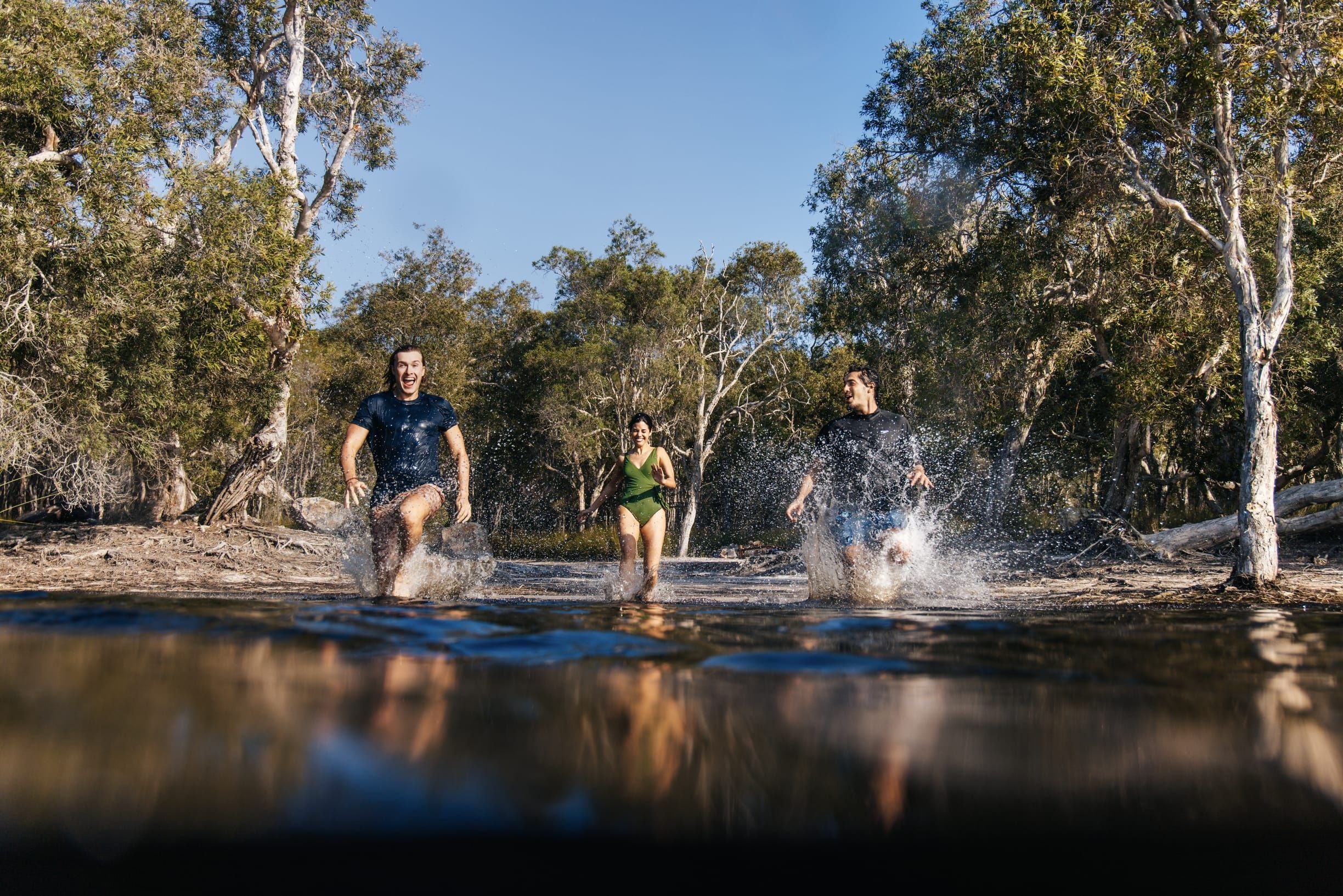 Friends splashing in Bummeria (Brown Lake) on Minjerribah, a naturally perched freshwater lake found just outside the township of Dunwich