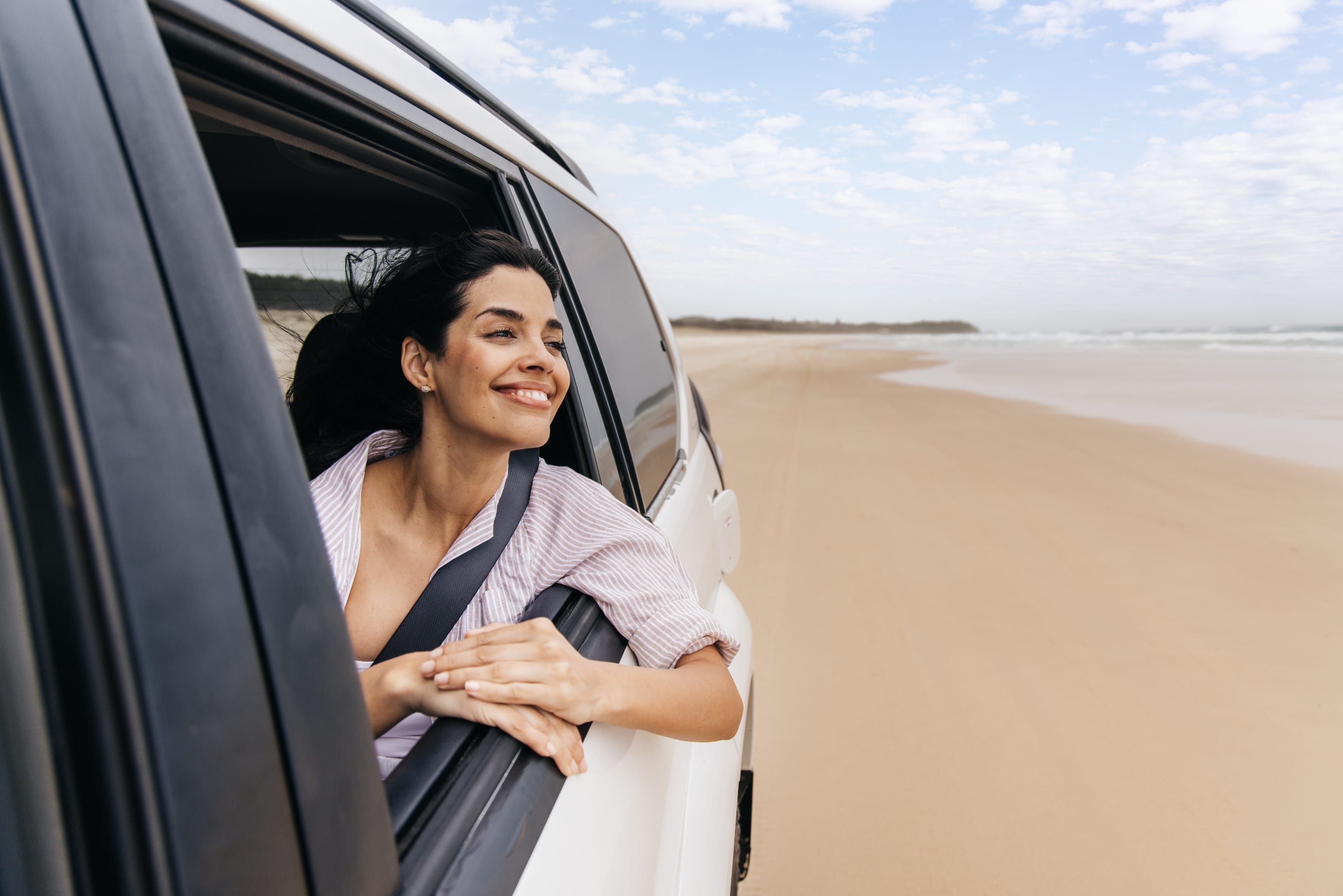 Woman looking out 4WD vehicle window while travelling along Main Beach, Minjerribah (North Stradbroke Island)