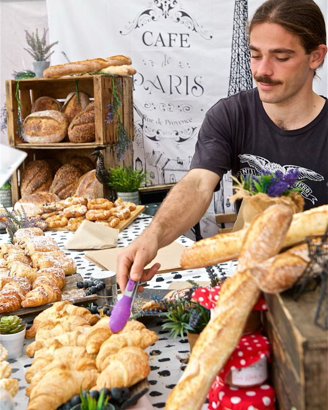 Male stall ownder serves pastries and baguettes at Jan Powers Farmers Market, Brisbane Powerhouse Male stall ownder serves pastries and baguettes at Jan Powers Farmers Market, Brisbane Powerhouse