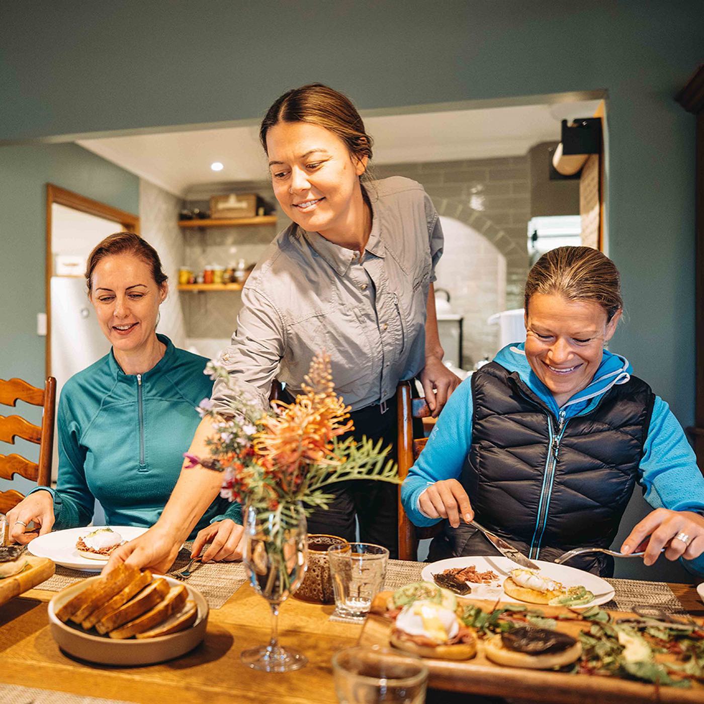 Waiter serves breakfast to two women sitting at a table of food Waiter serves breakfast to two women sitting at a table of food