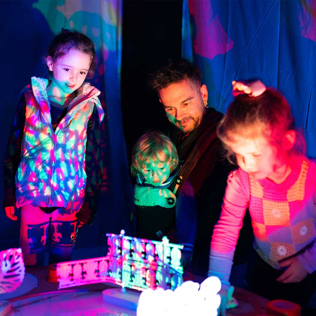 Three kids and father explore an interactive light installation Three kids and father explore an interactive light installation