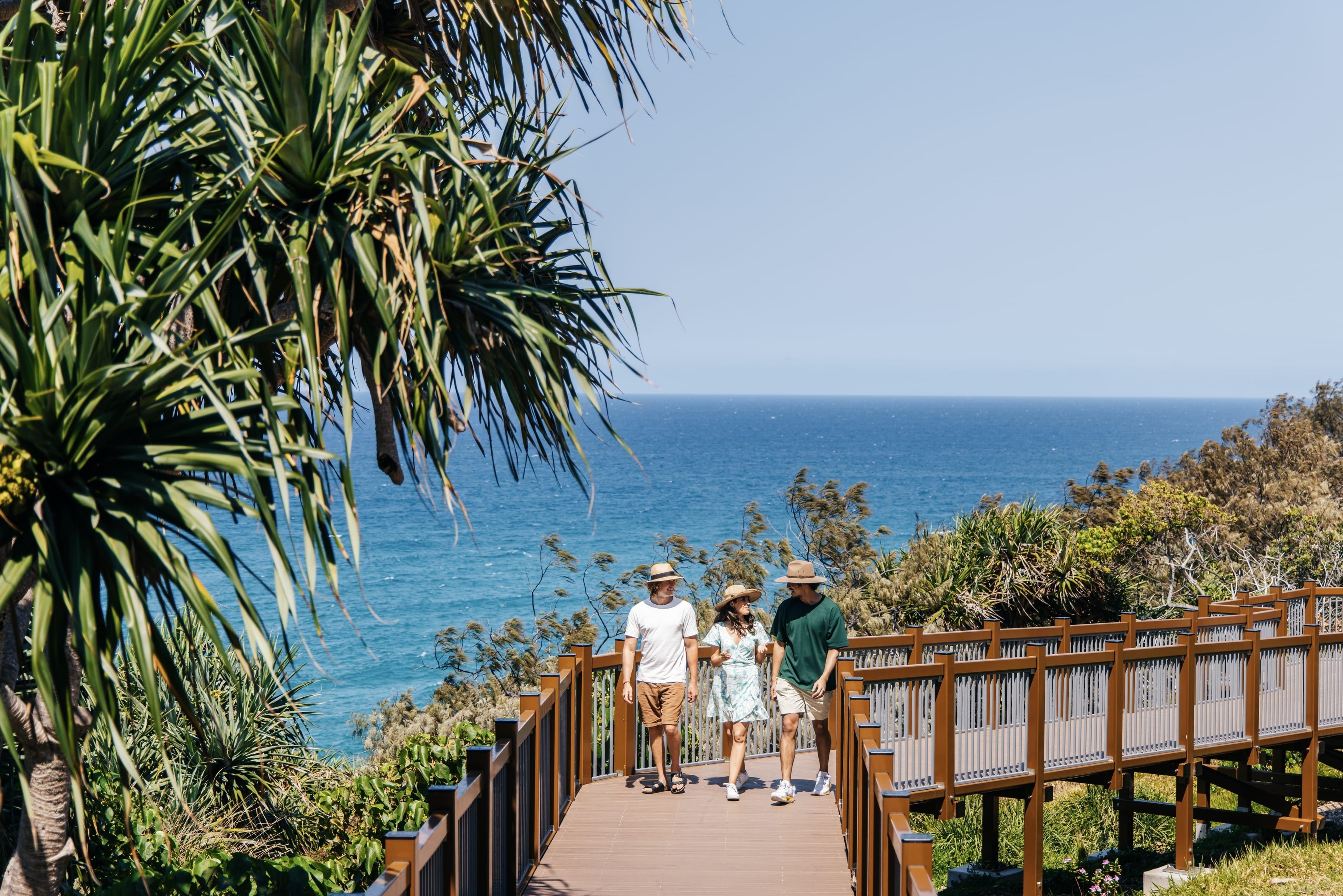 three friends walk along coastal boardwalk