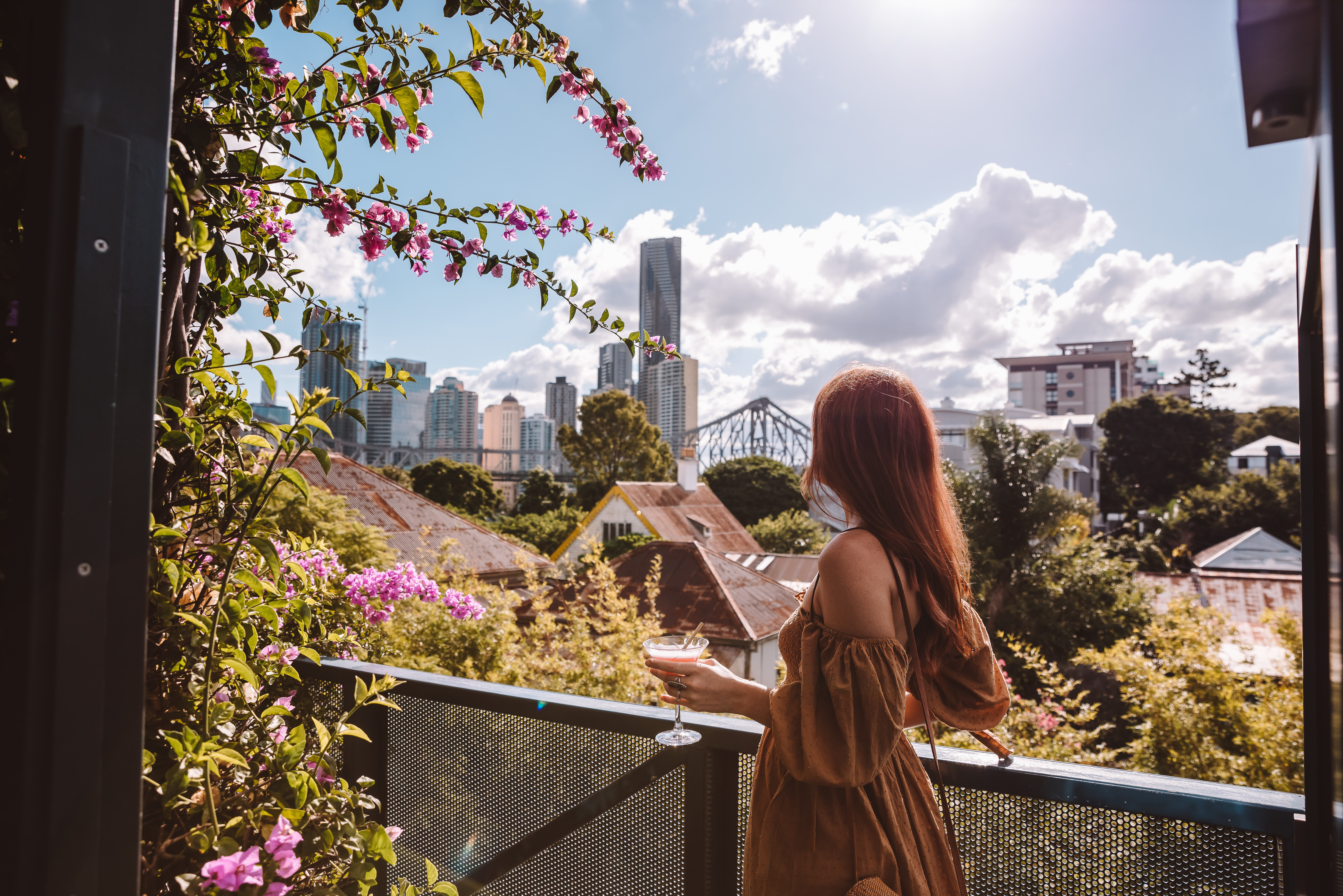 Lady enjoying a drink at the rooftop bar at Spicers Balfour Hotel, with city and Story Bridge in the distance