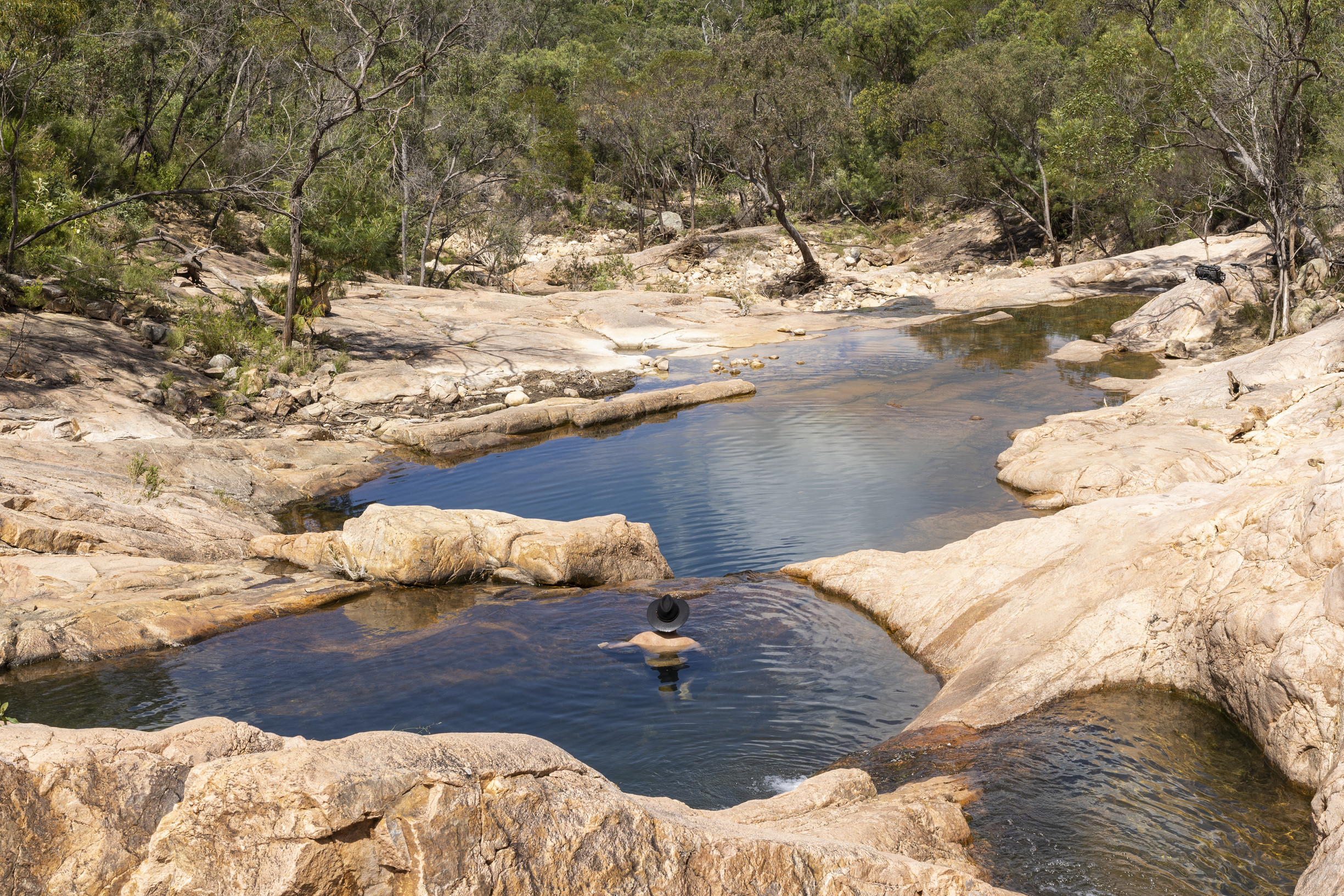 Man swimming in rock pools surrounded by bushland Man swimming in rock pools surrounded by bushland