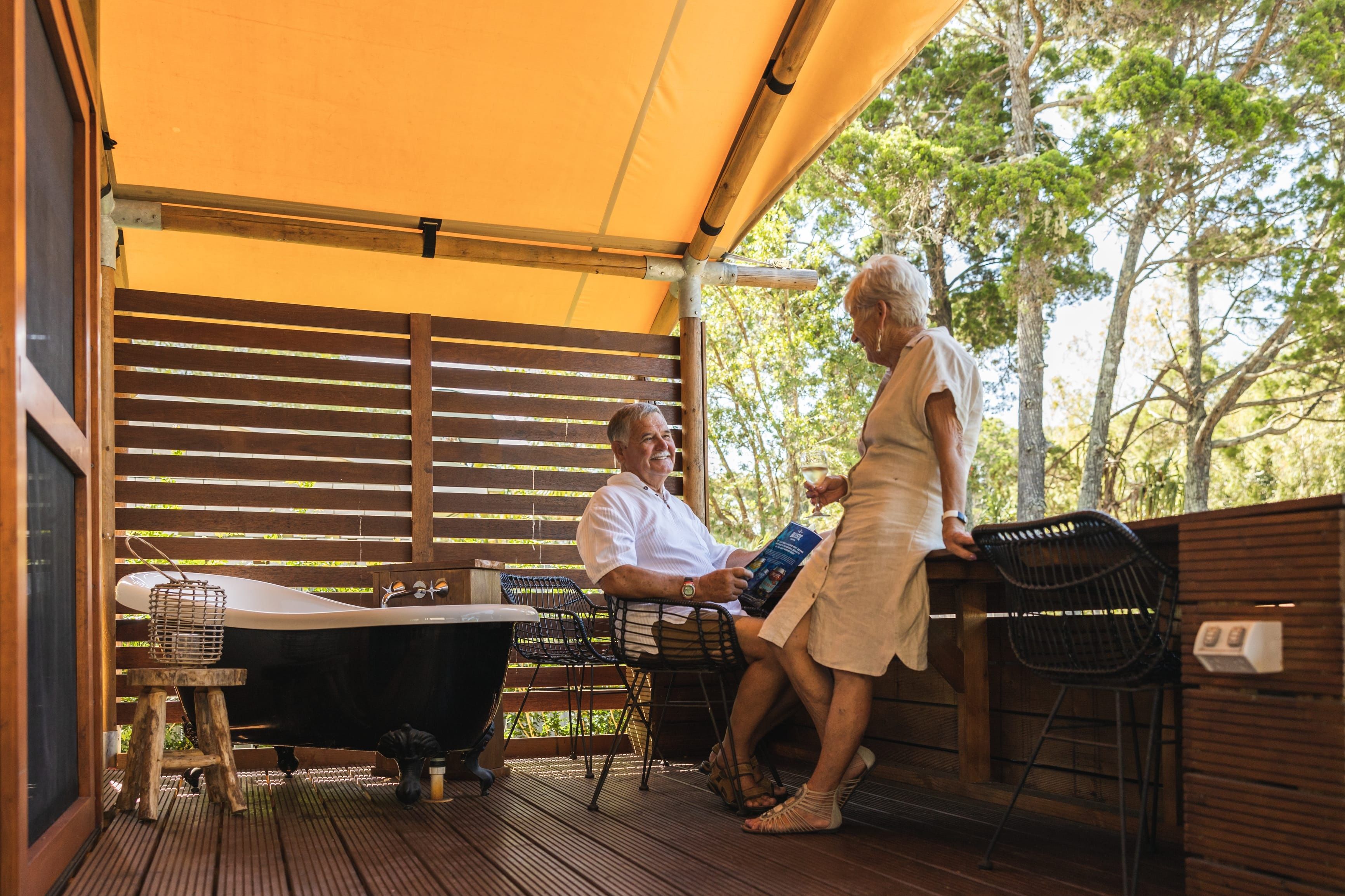 Couple relaxing on the deck of their cabin at NRMA Woodgate Beach Holiday Park