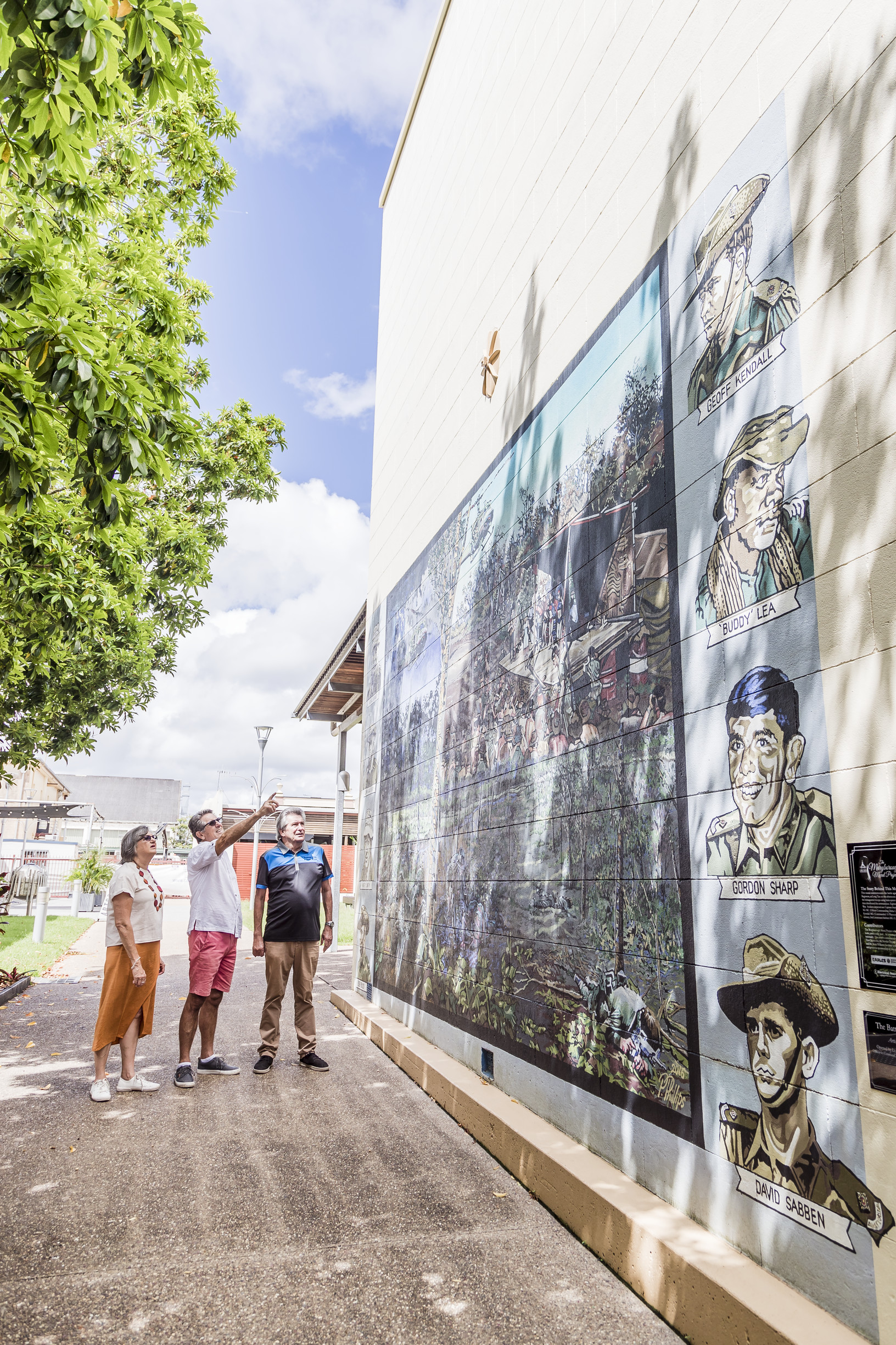 Couple with a tour guide look at large historic murals outside a museum Couple with a tour guide look at large historic murals outside a museum
