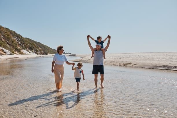 Parents and two kids walking along the beach together Parents and two kids walking along the beach together