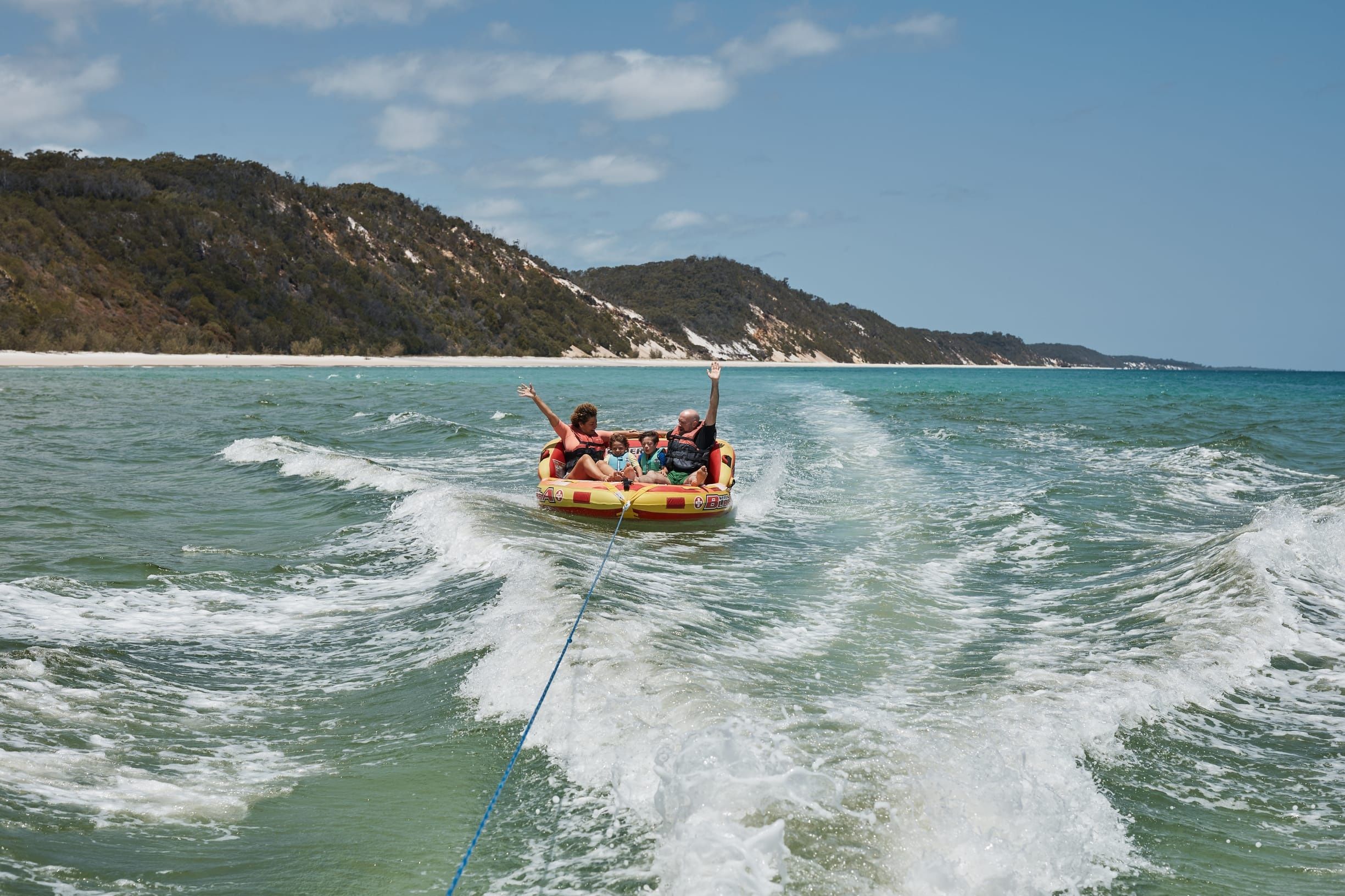 Family of four tubing behind a boat off a remote island
