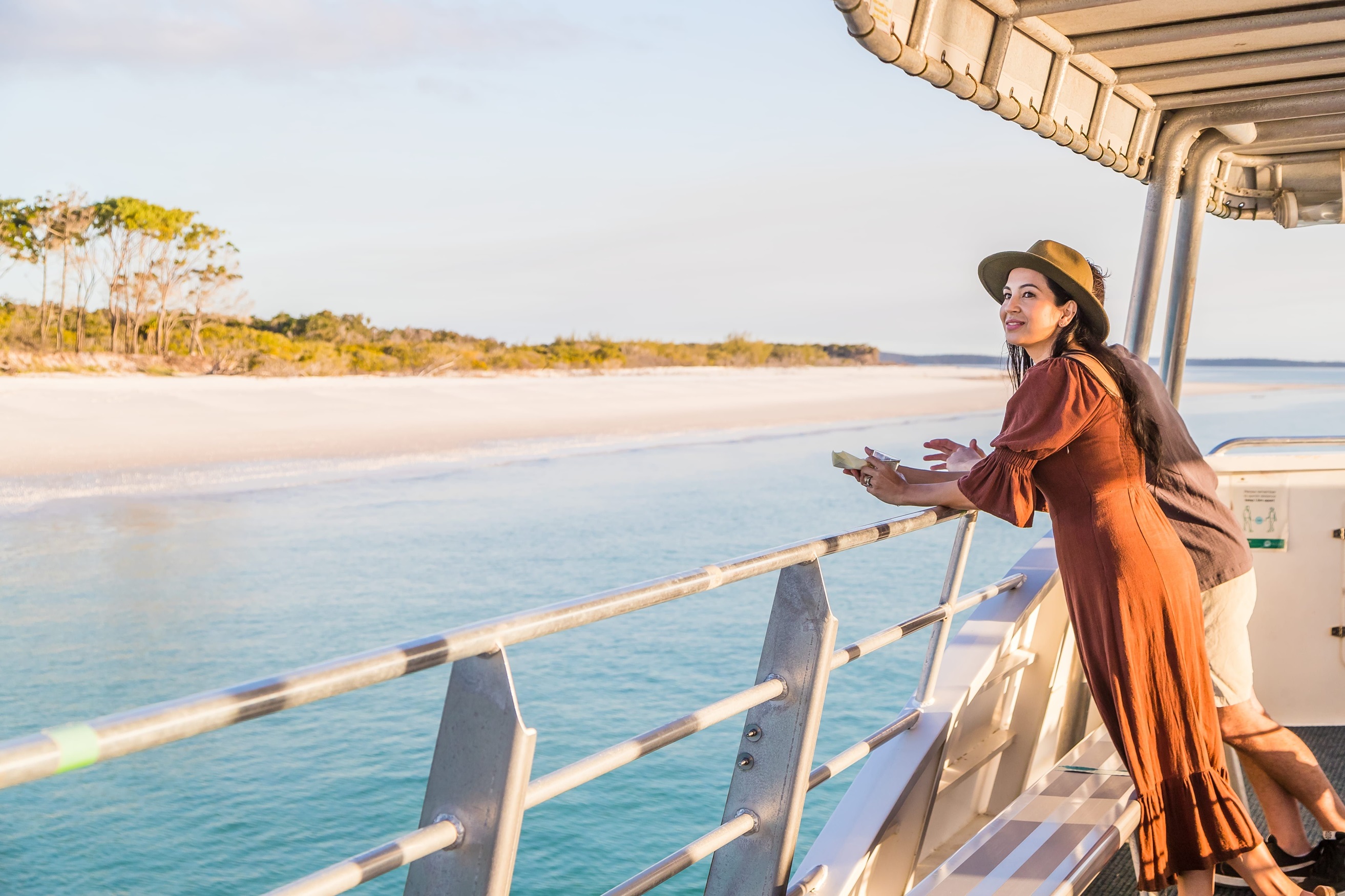 Woman stands on open deck of a boat during a sunset cruise Woman stands on open deck of a boat during a sunset cruise