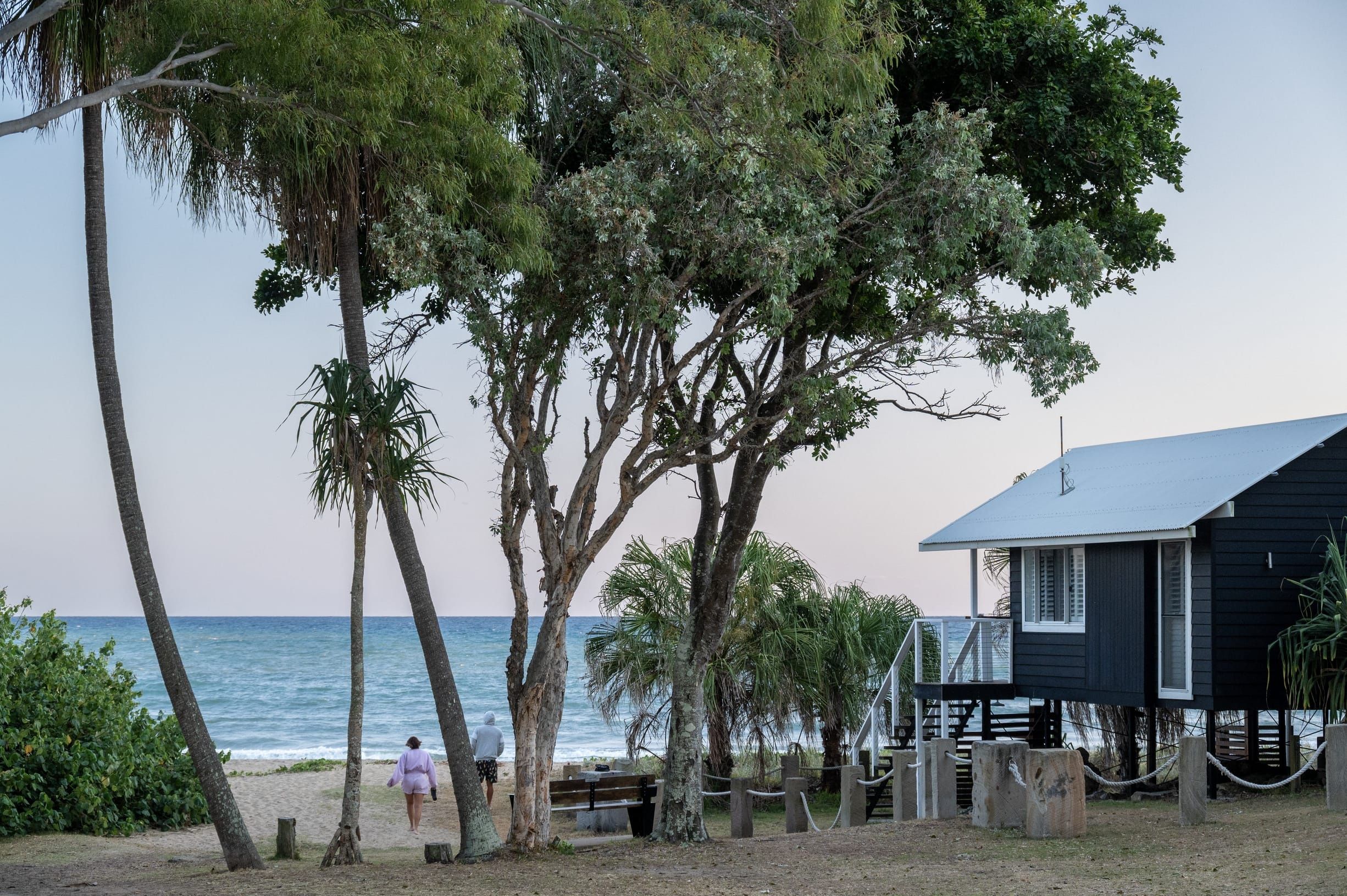 Couple walk along the sand to the beach beside beachfront holiday park accommodation