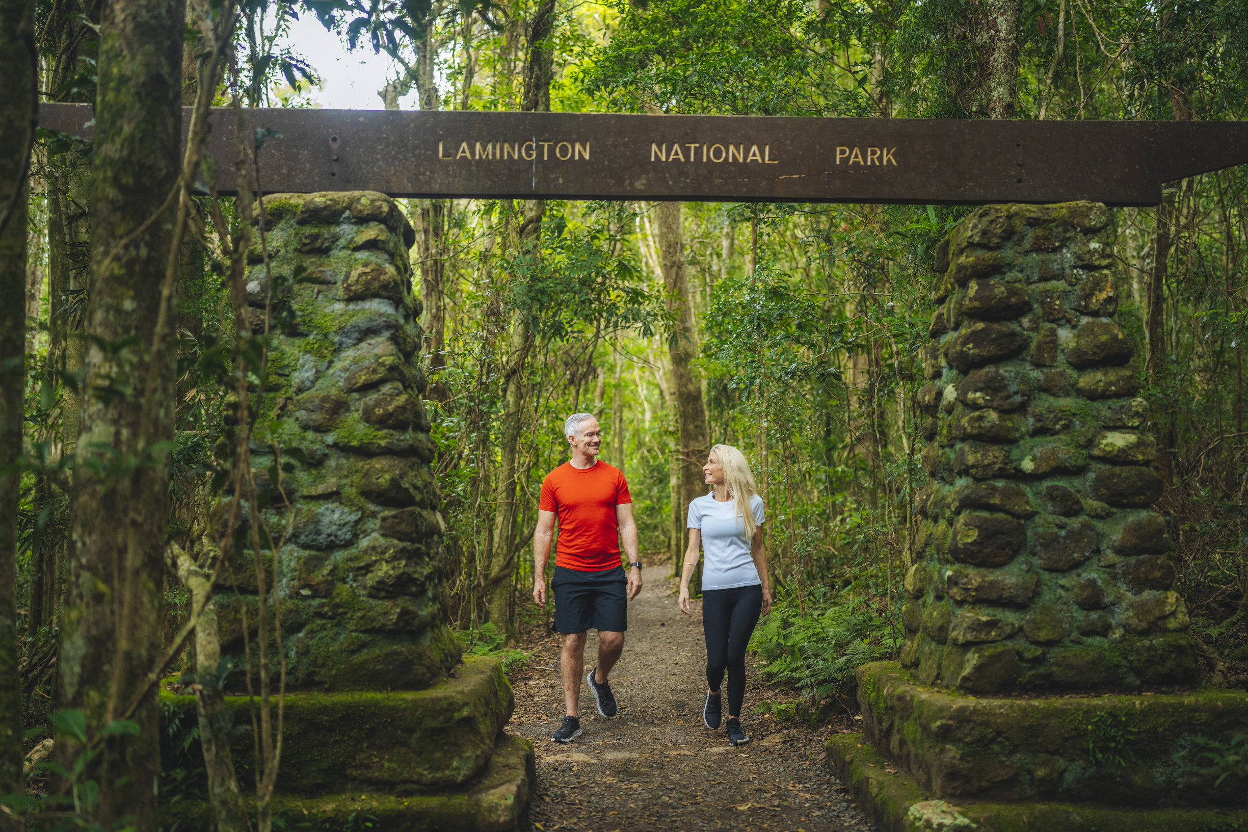 Couple walking through a sign, that says Lamington National Park