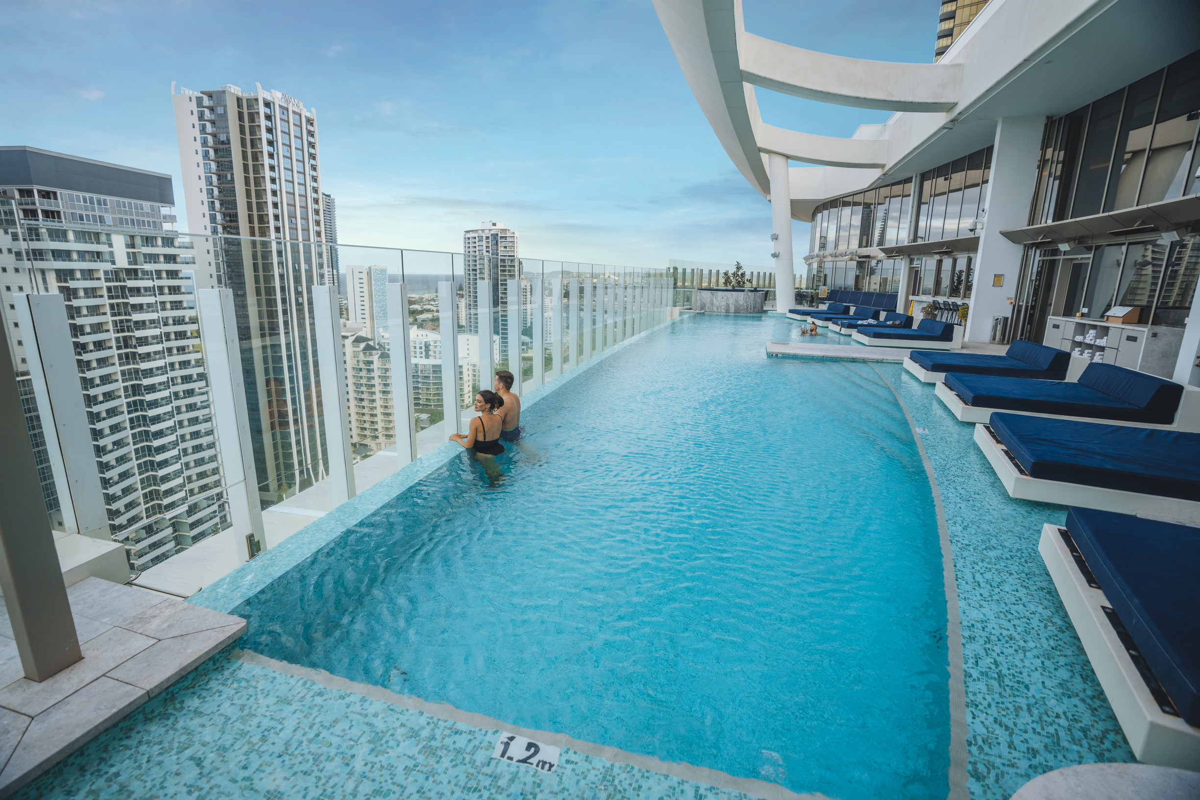 Couple relaxing a rooftop pool with city skyline views at Nineteen at The Star, in The Darling Couple relaxing a rooftop pool with city skyline views at Nineteen at The Star, in The Darling