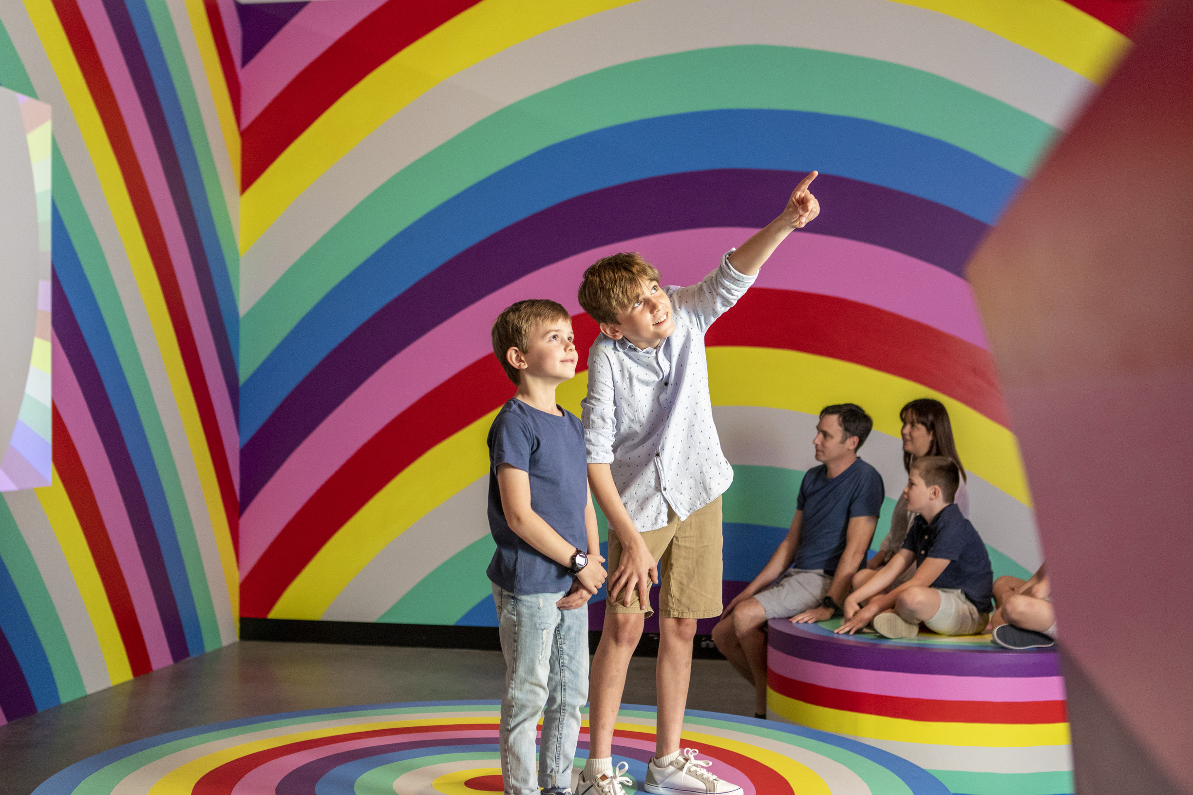 Family looking at the colourful Rainbow Meditation Room at HOTA, Home of the Arts