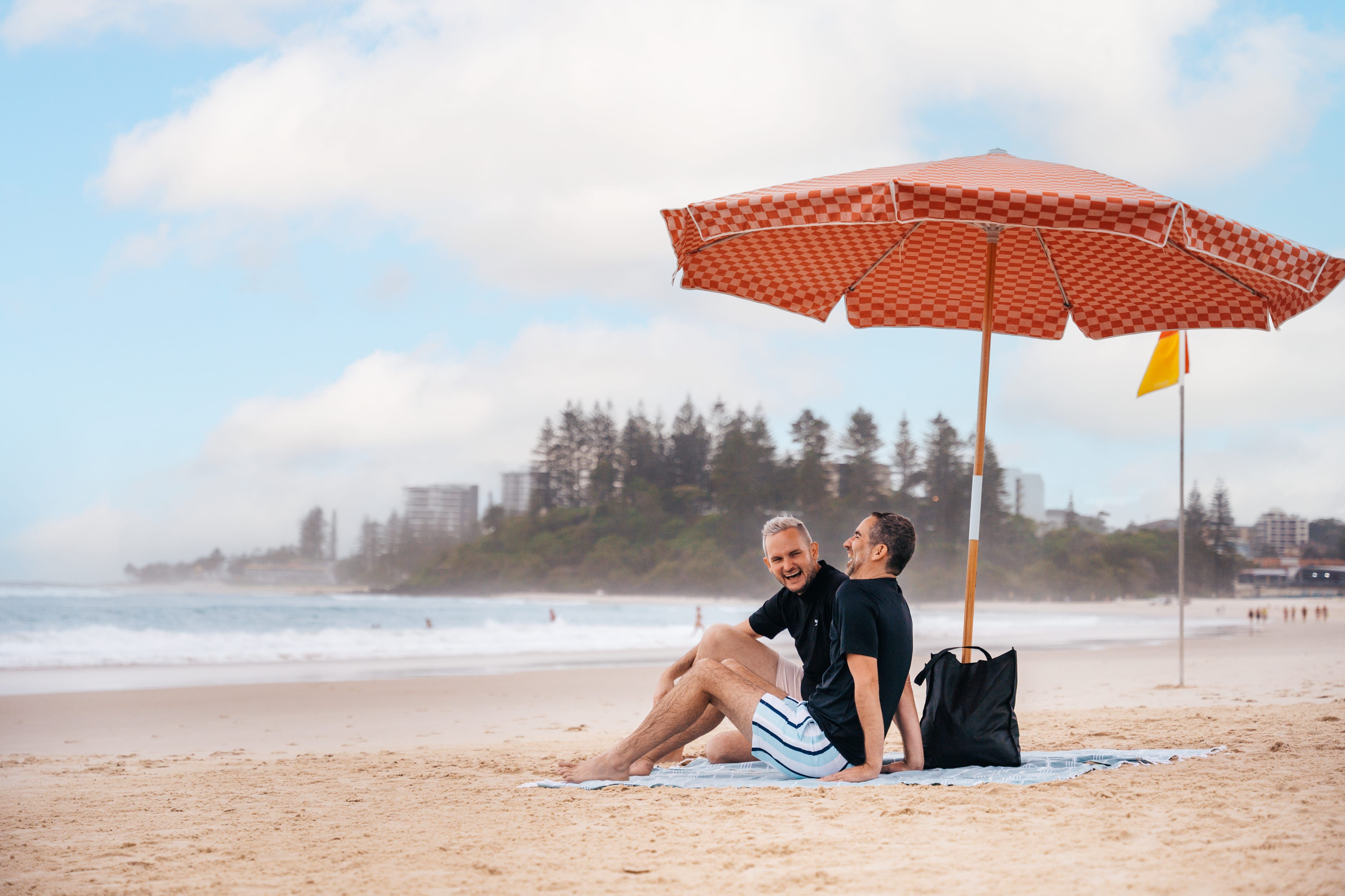 A couple sitting under a sun umbrella on Coolangatta Beach A couple sitting under a sun umbrella on Coolangatta Beach