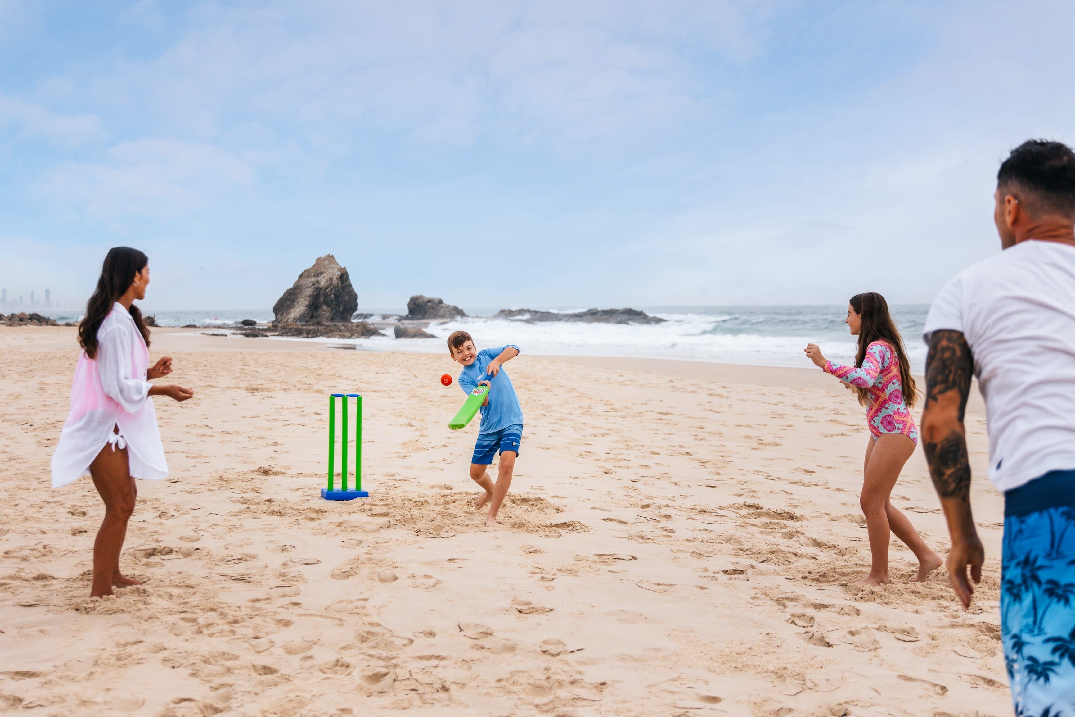Family playing cricket on Currumbin Beach, Gold Coast