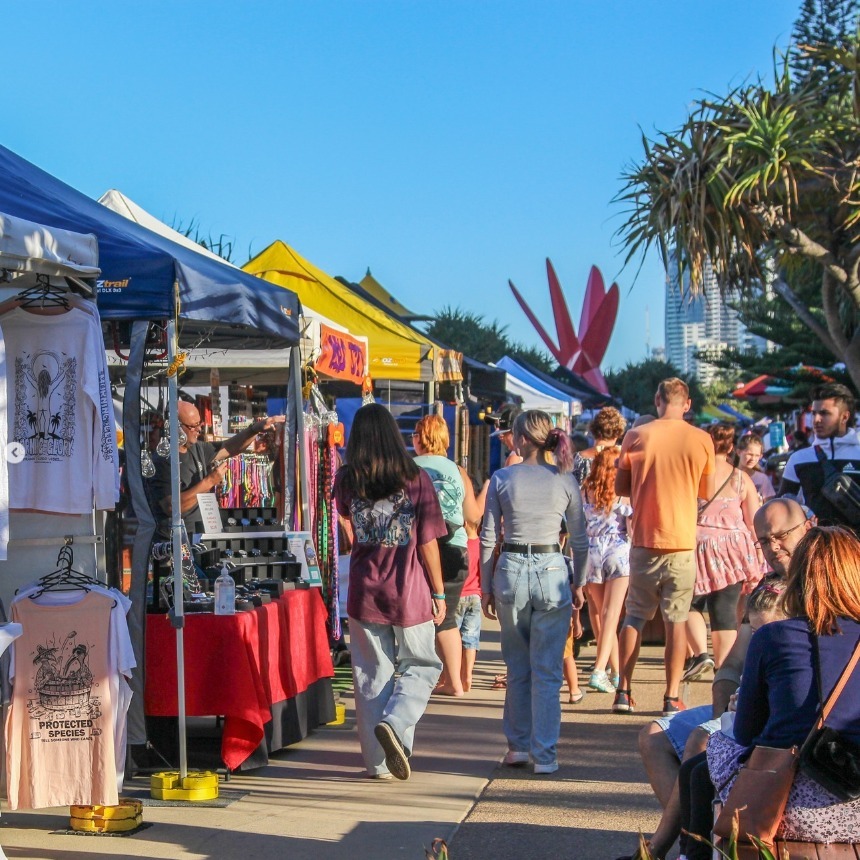 Crowds of shoppers walk past stalls at Surfers Paradise Beachfront Markets on a sunny day