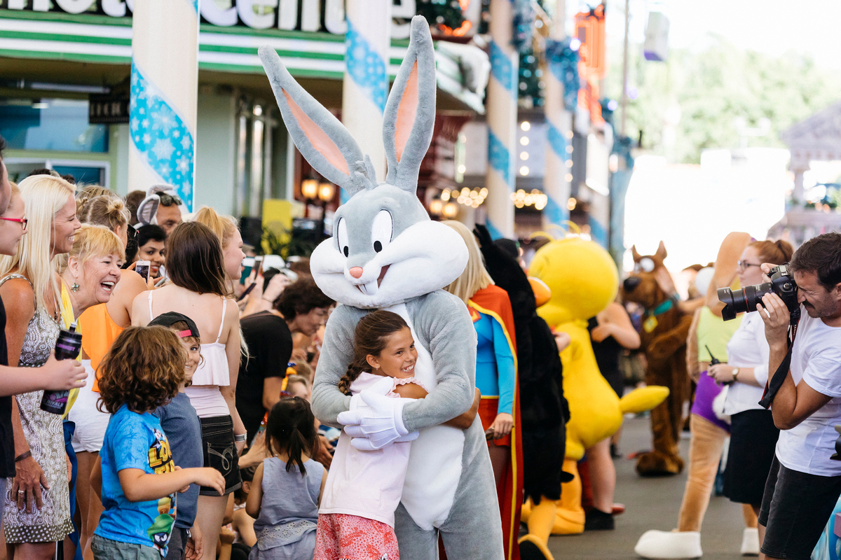 Young girl hugs Bugs Bunny mascot during The Star Parade at Movie World Gold Coast