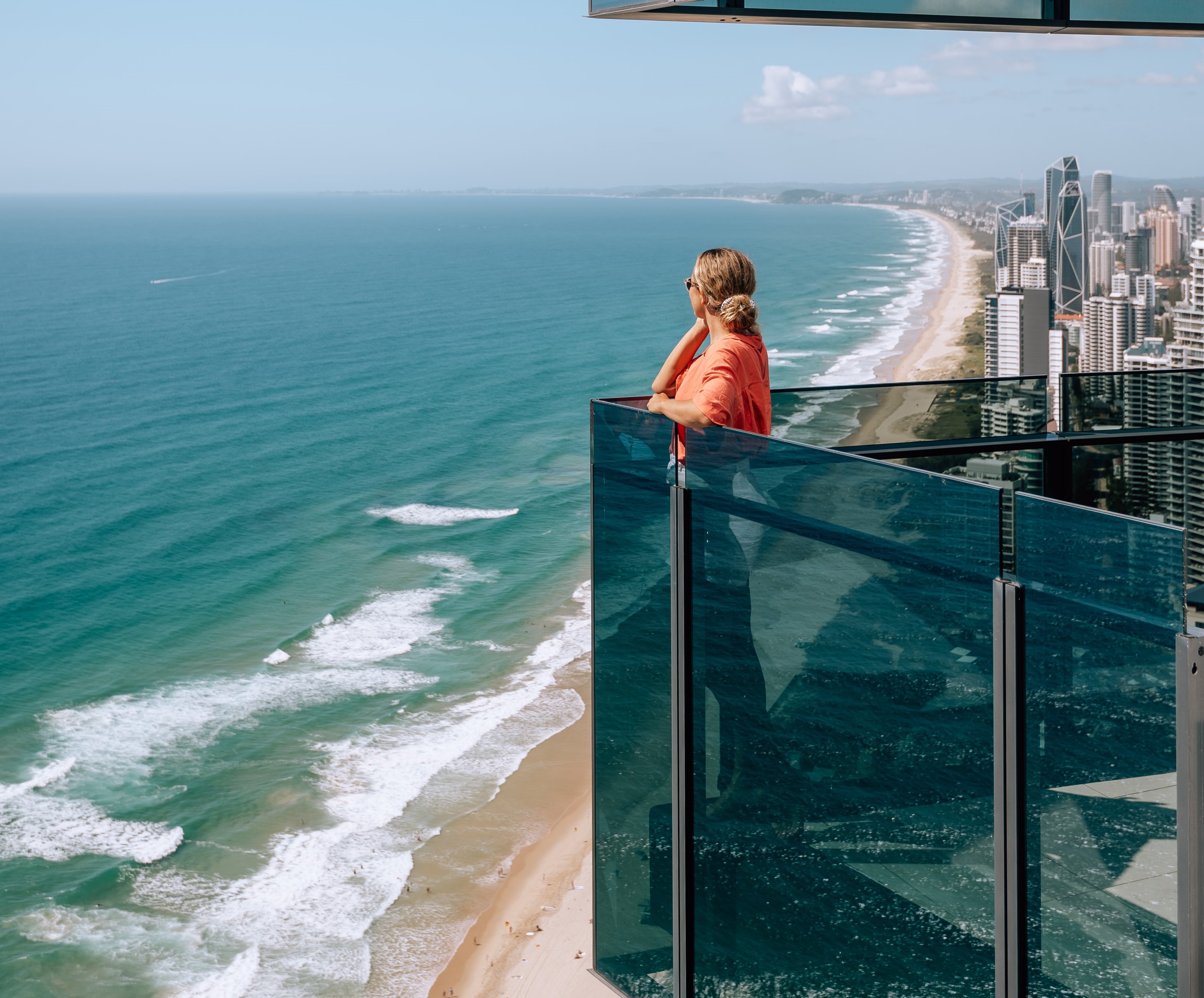 Woman stands on hotel balcony overlooking the beach