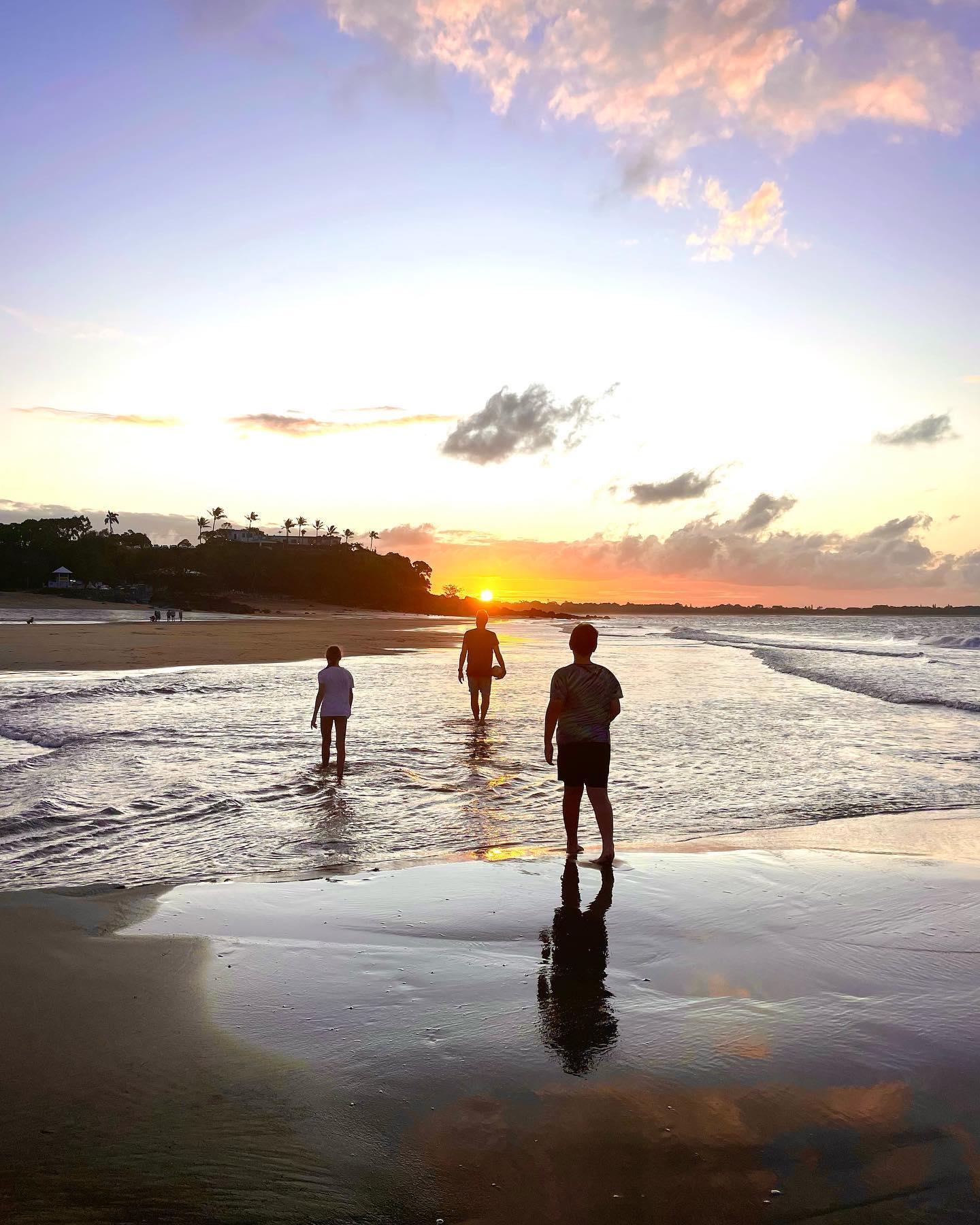 Family wade through shallow waters at sunset on Eimeo Beach, Mackay Family wade through shallow waters at sunset on Eimeo Beach, Mackay