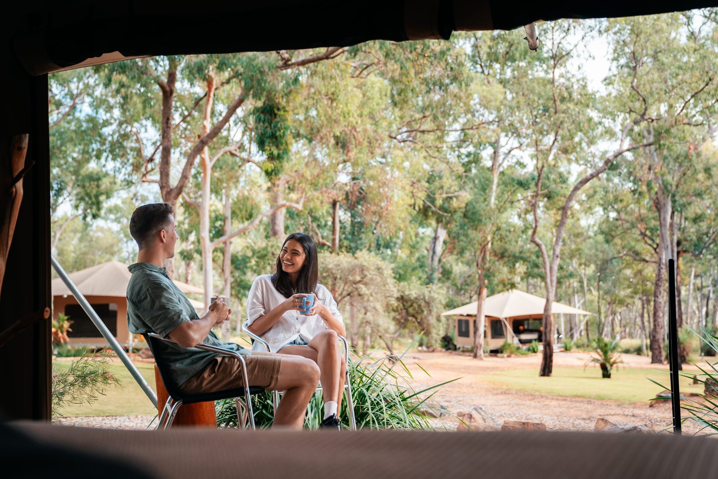 Couple relax with a cup of tea outside their glamping tent among the bush at Wallaroo Outback Retreat