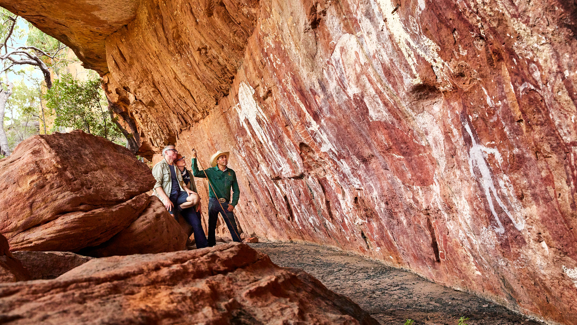 A local guide and a couple looking at ancient rock art A local guide and a couple looking at ancient rock art