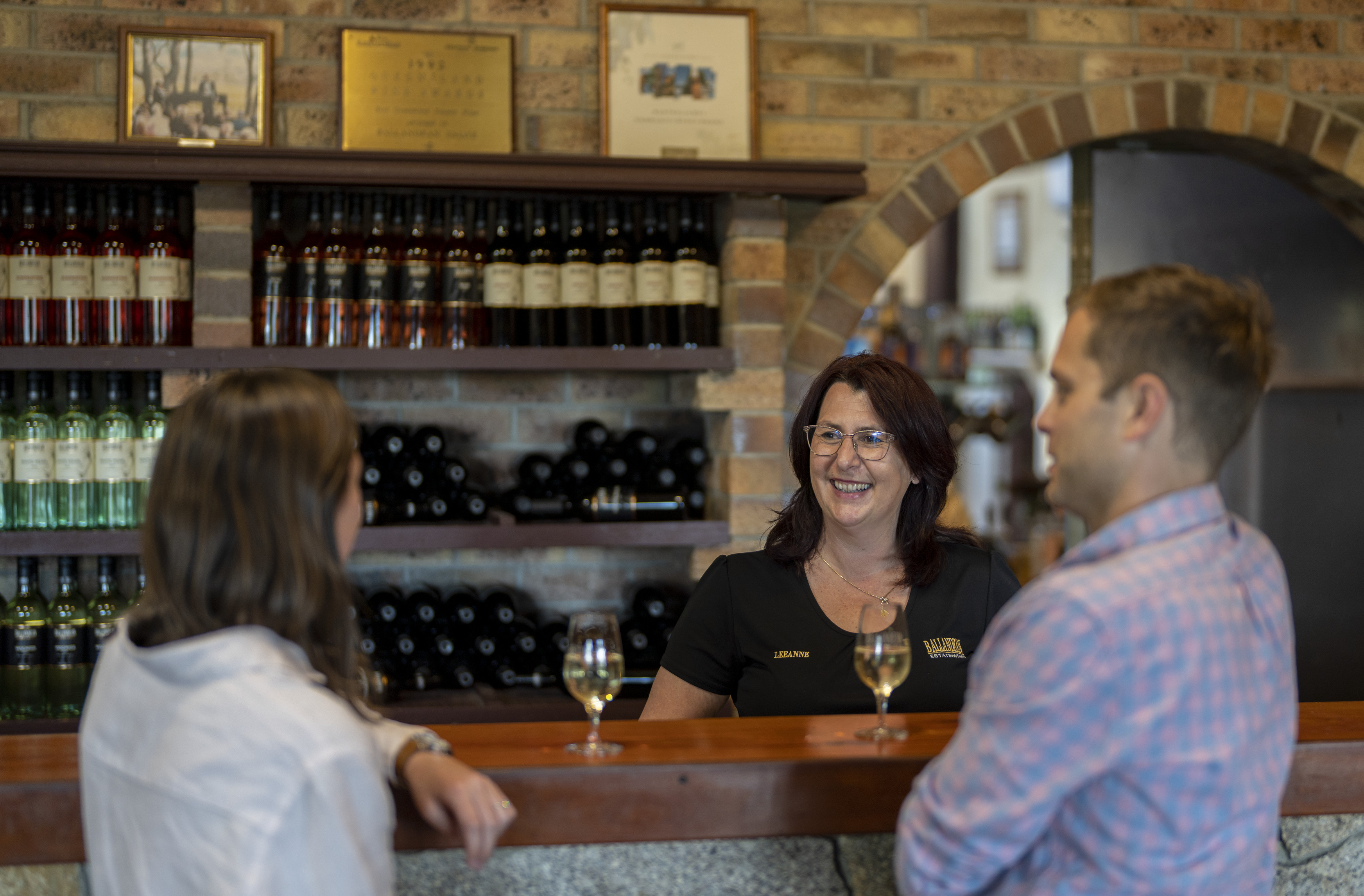 Couple enjoying a glass of wine at the cellar door, while chatting with Leeanne Puglisi-Gangemi from Ballandean Estate Wines | Granite Belt wineries