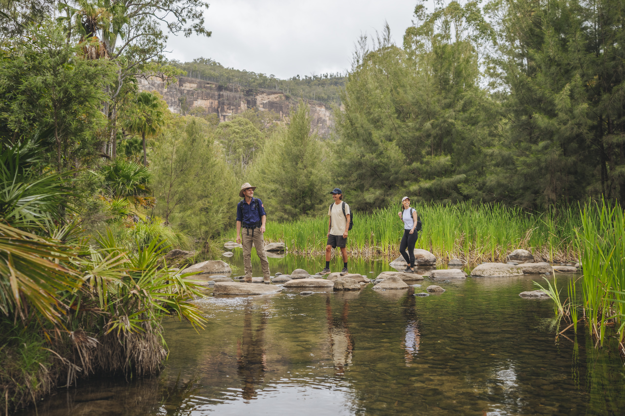 Two hikers on a guided walk along stepping stones in a river