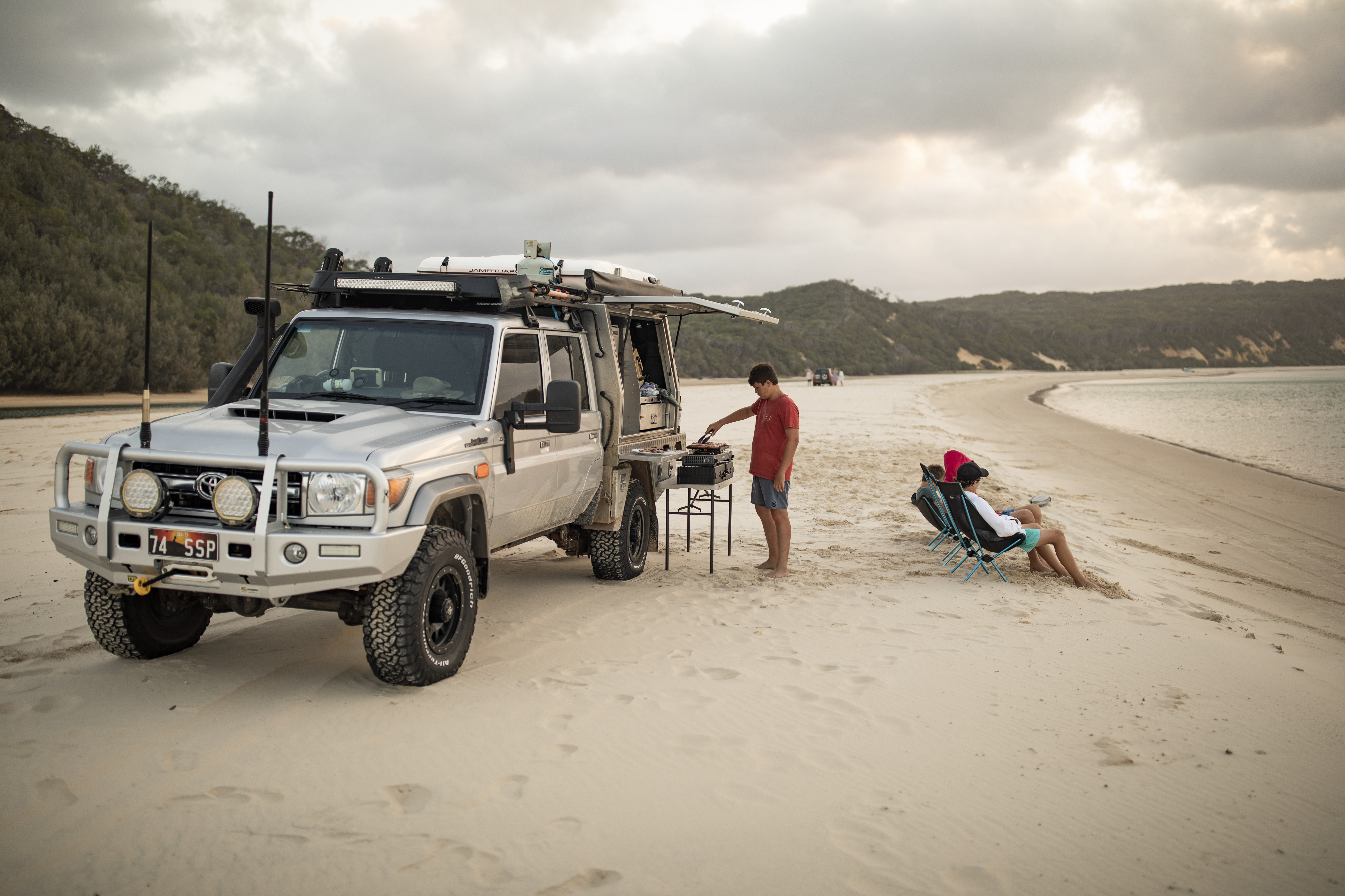 Campers park a 4WD on the sand at a beach Campers park a 4WD on the sand at a beach