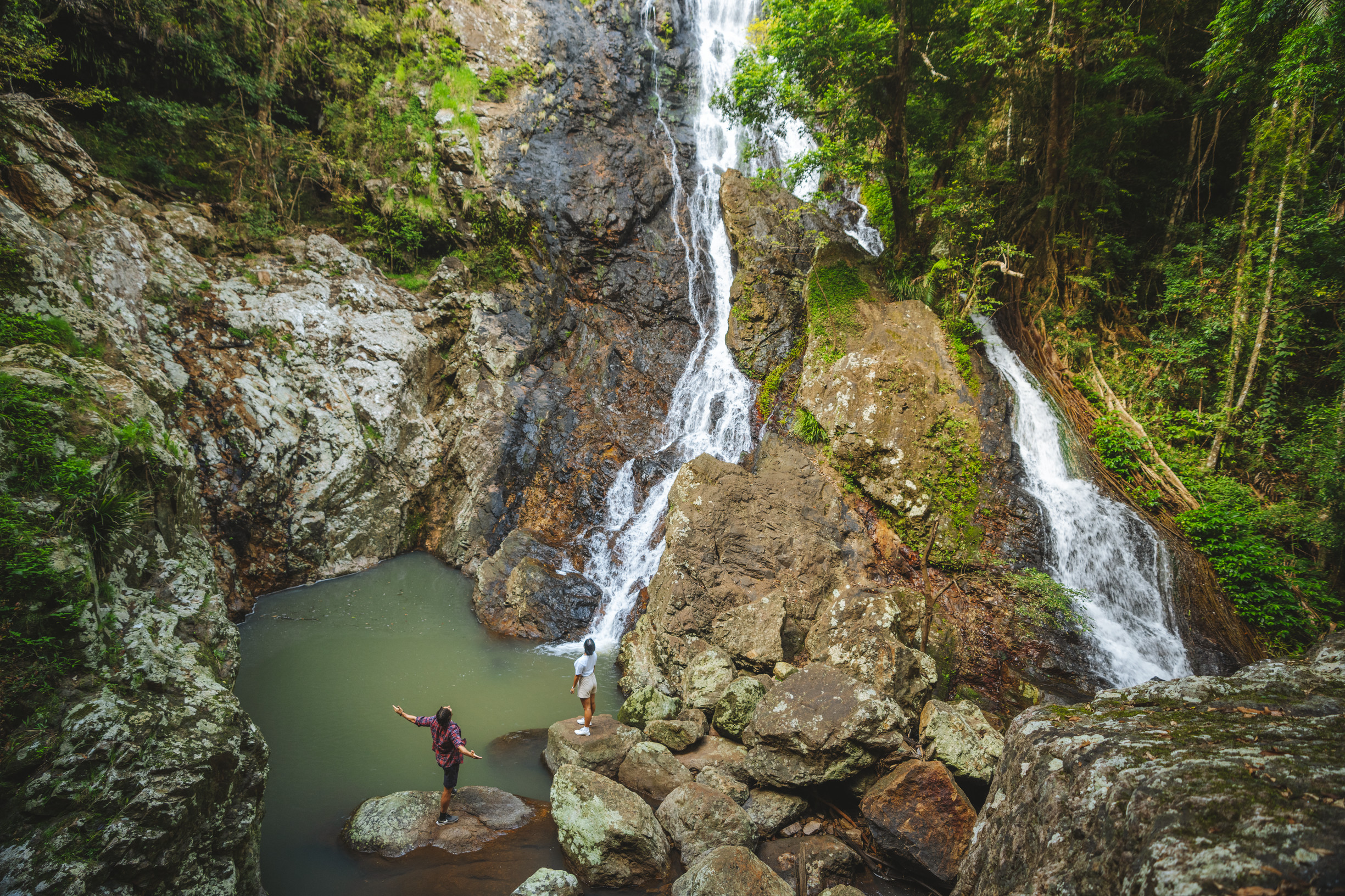 Hikers stand at the bottom of a waterfall