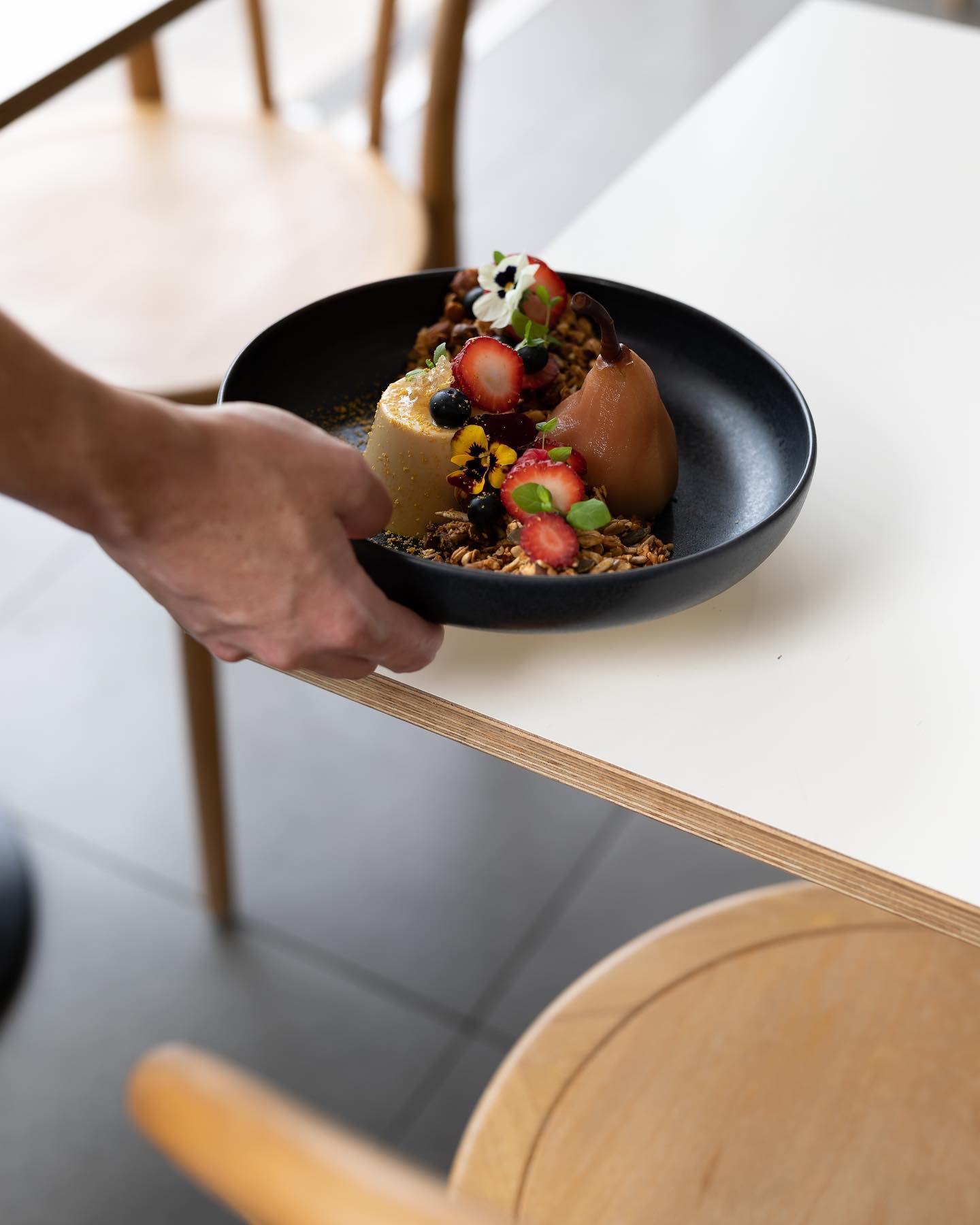 A hand placing a breakfast dish onto a table at a cafe