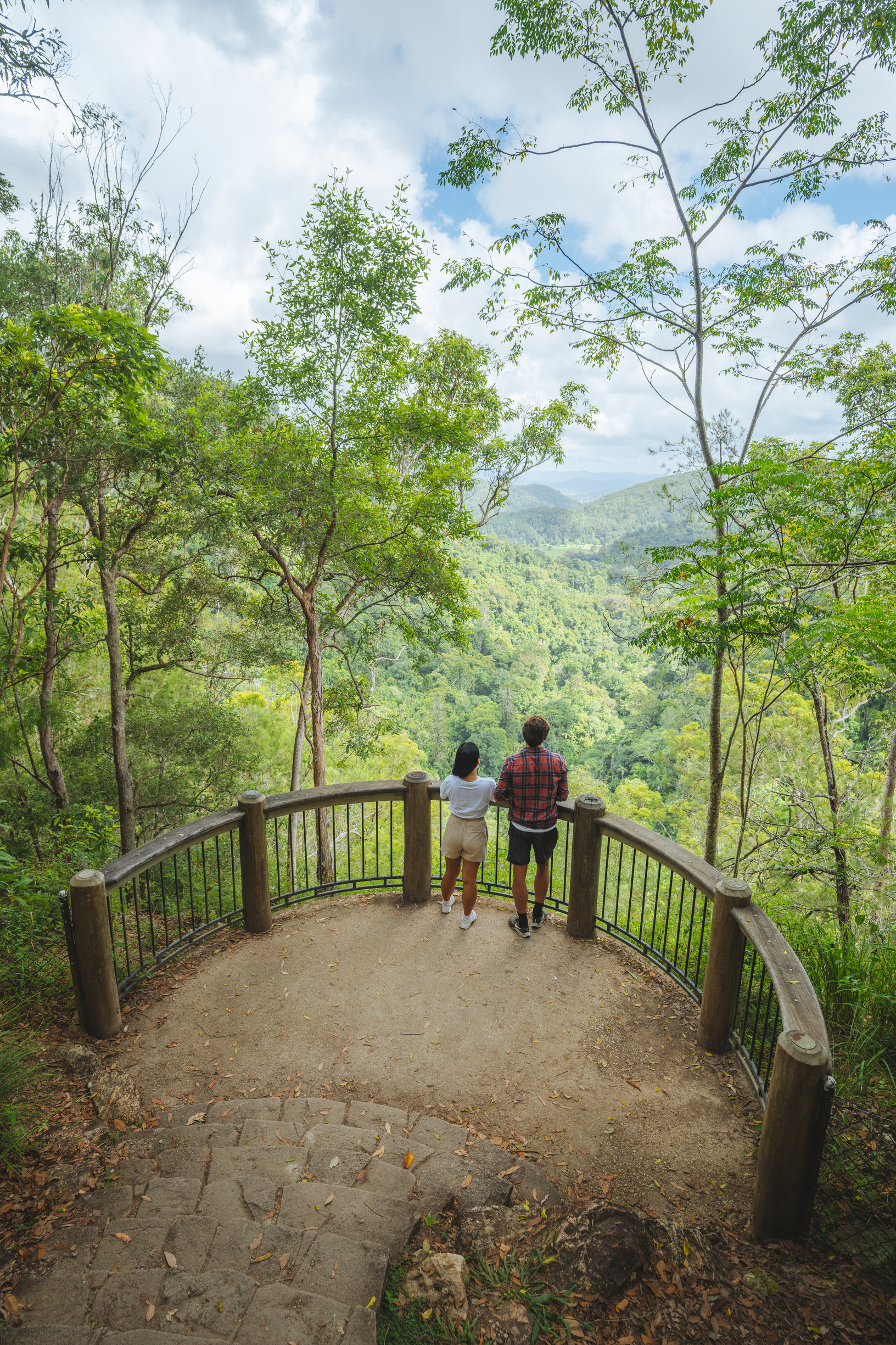 Couple looking at views of rolling hills and hinterland from a lookout at Kondalilla National Park