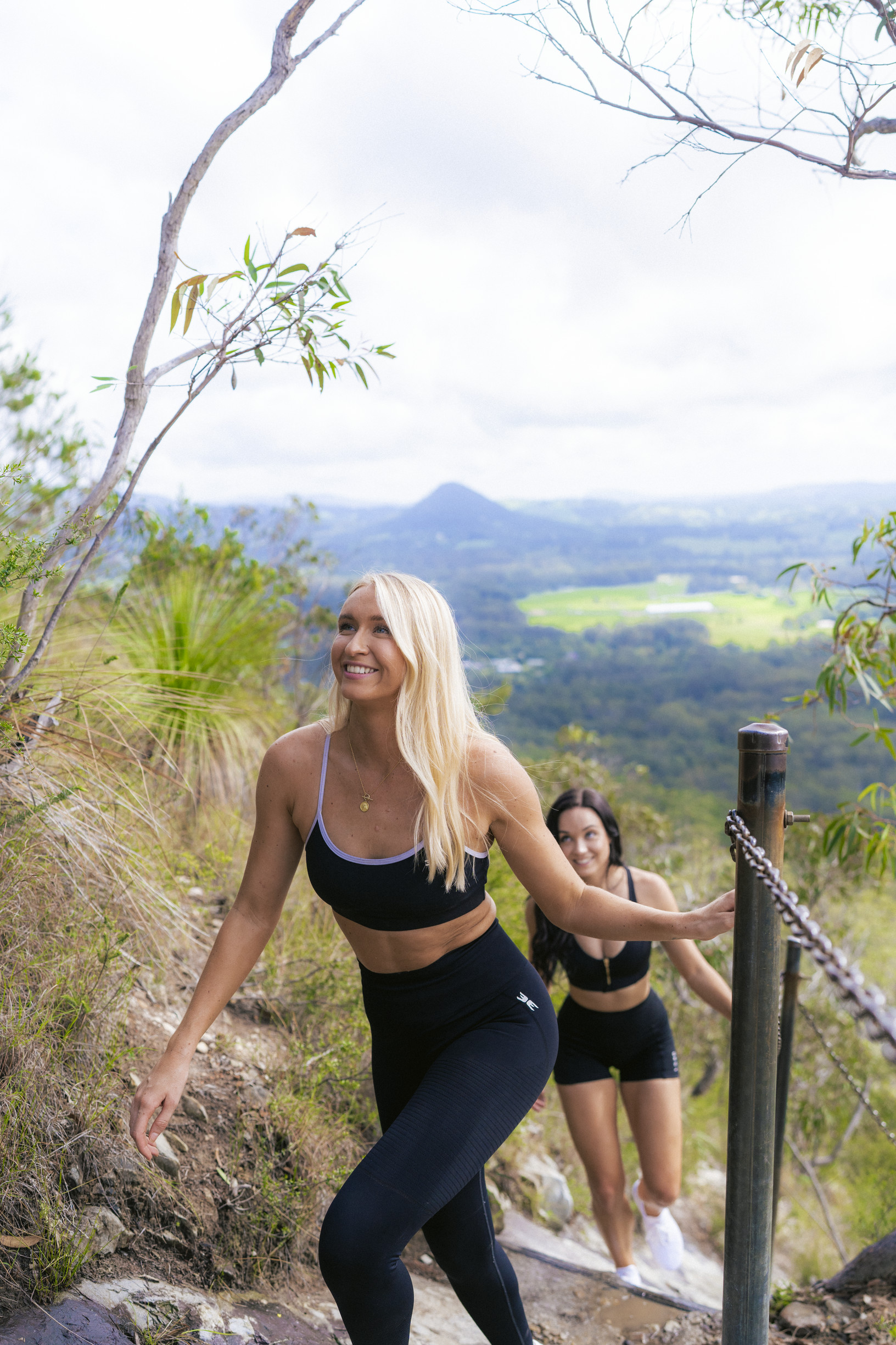 Two ladies walking along a mountain trail surrounded by bushland