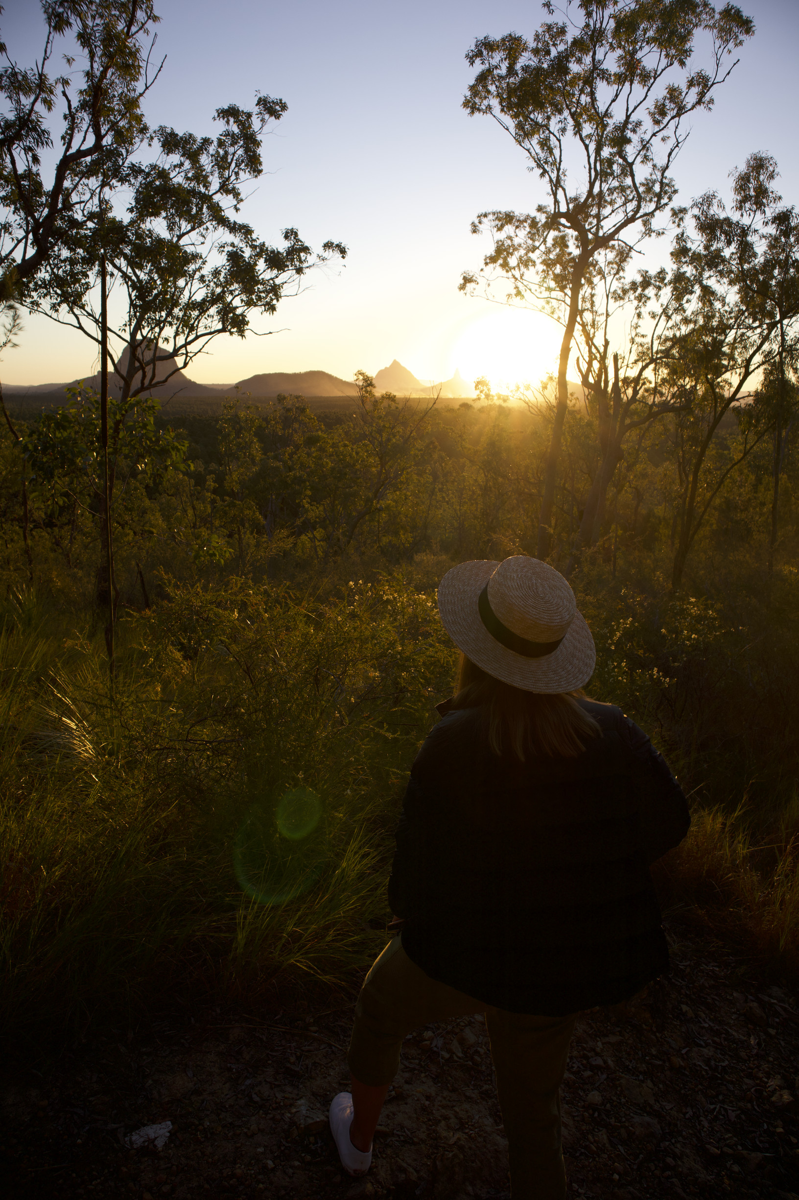 Woman watches sunrise over mountains from a lookout