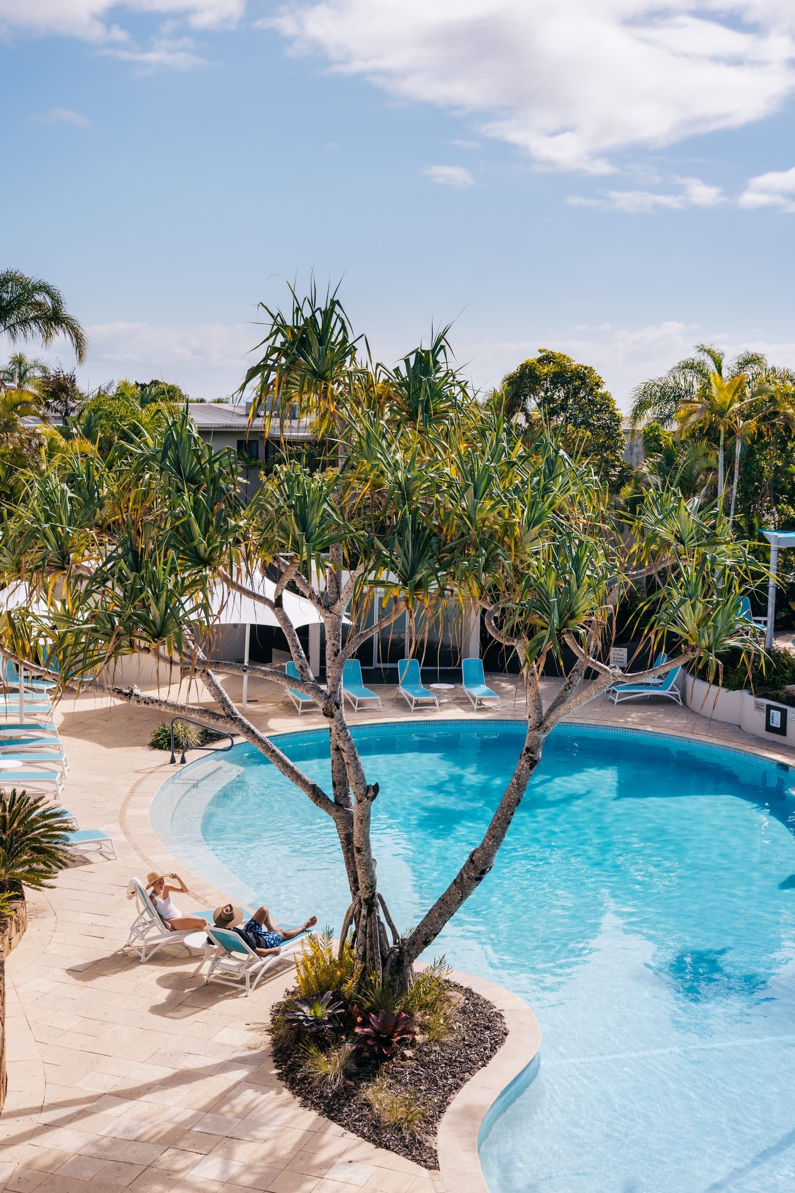 Couple relax in lounge chairs by the pool at Noosa Blue Resort