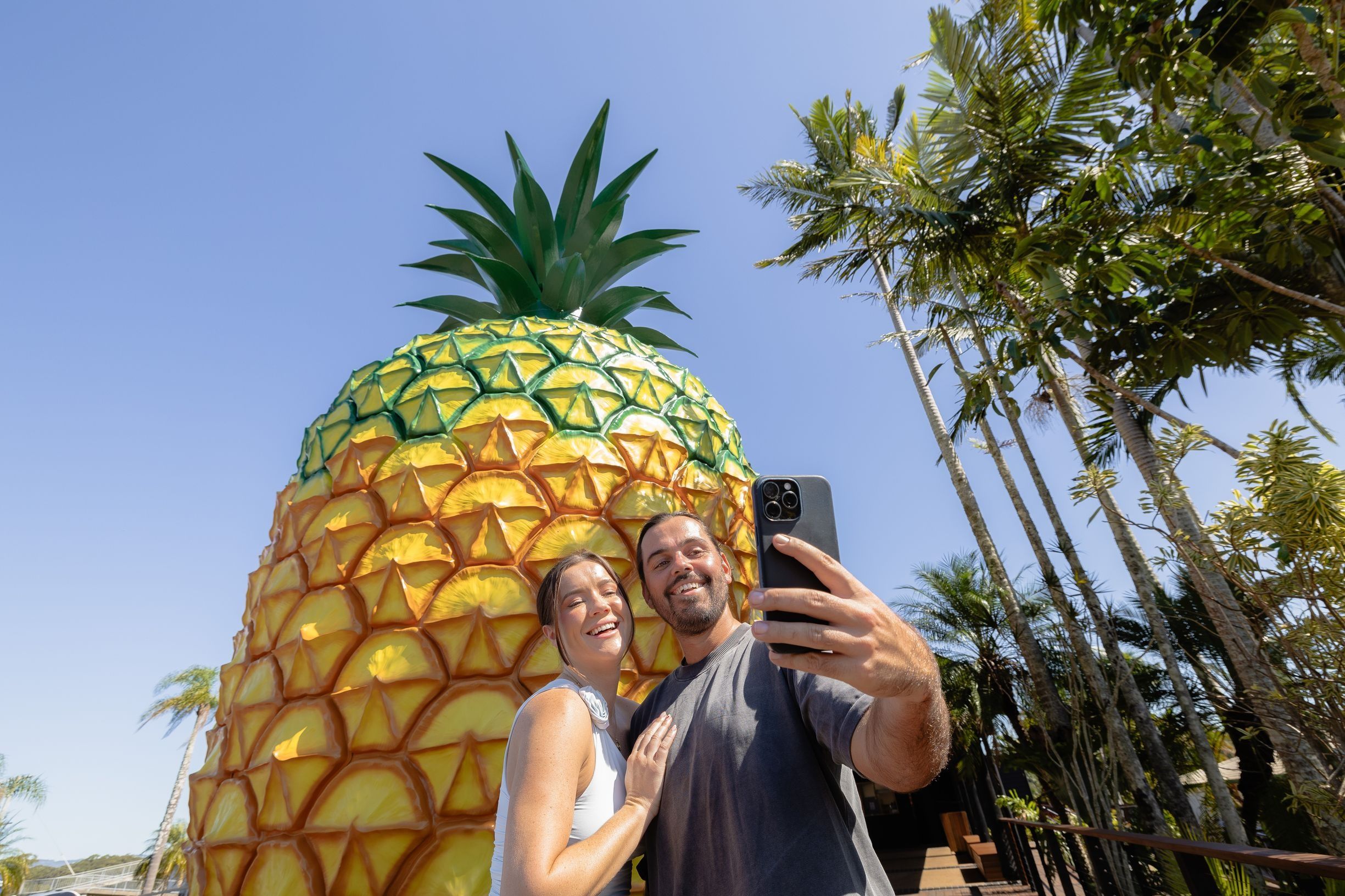 Couple taking selfie in front of The Big Pineapple landmark